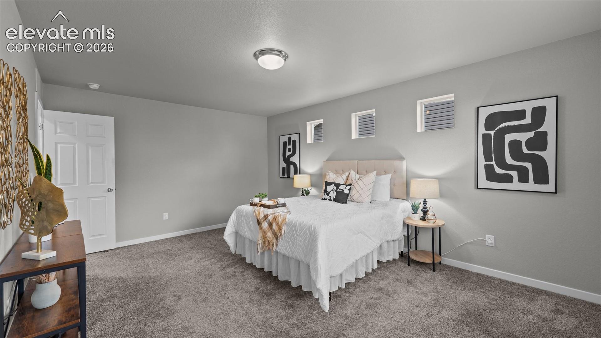Neutral-toned interior space featuring carpeting, smooth-finish walls, three high-placed rectangular windows, and a flush-mount ceiling fixture