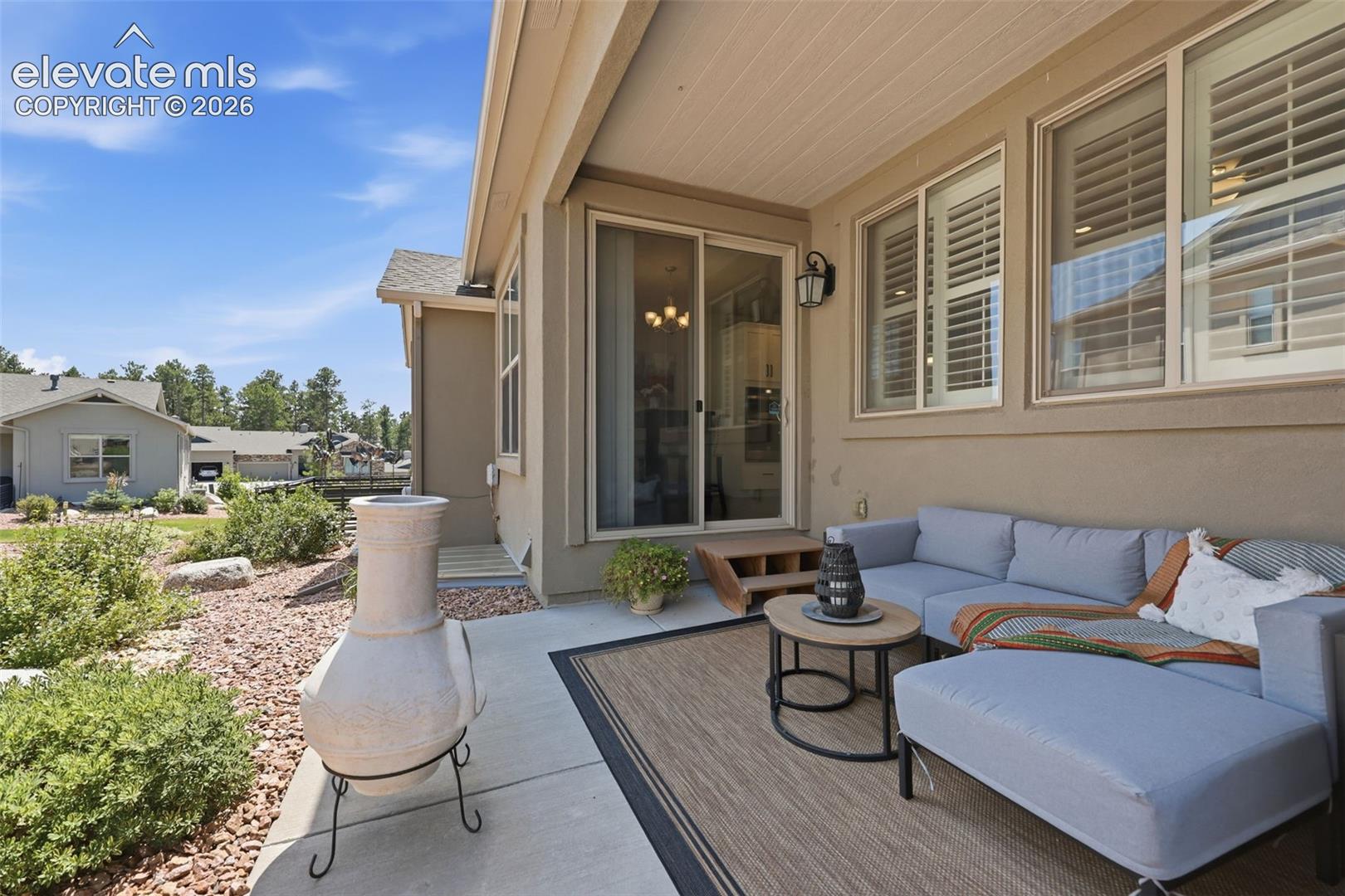 Covered outdoor patio with a stucco exterior and white window shutters.