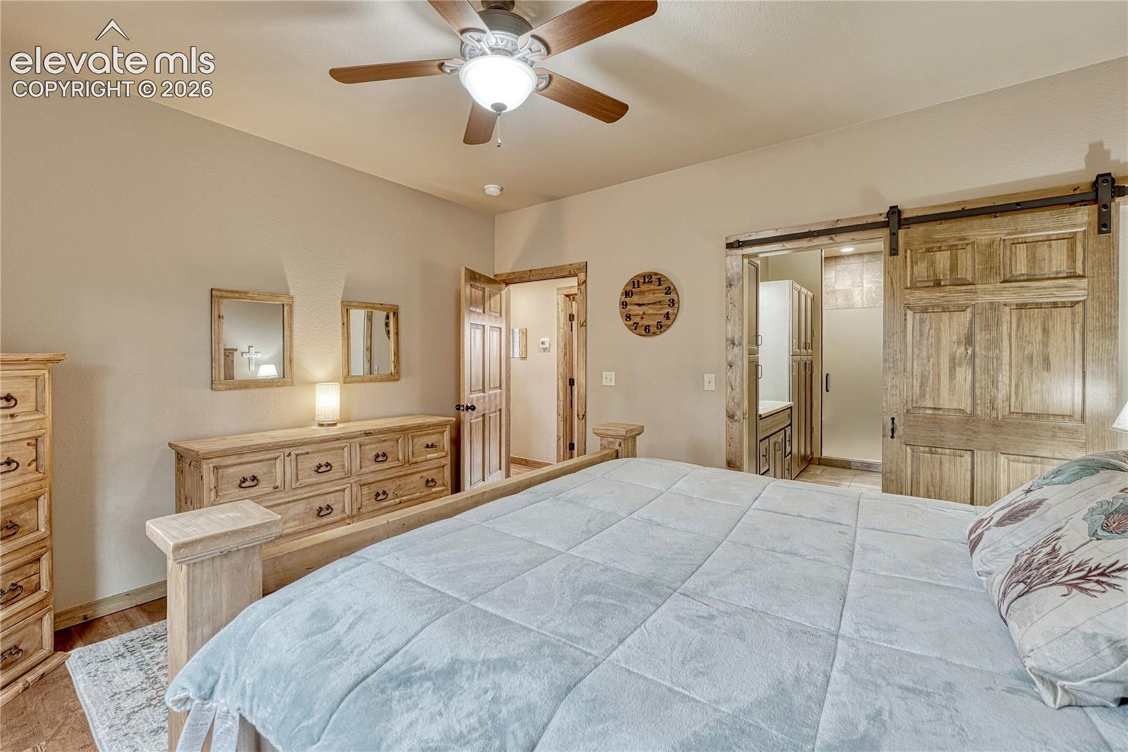 Interior space featuring a sliding wood-panel barn door, ceiling fan with integrated lighting, wood-trim door casing, and recessed lighting