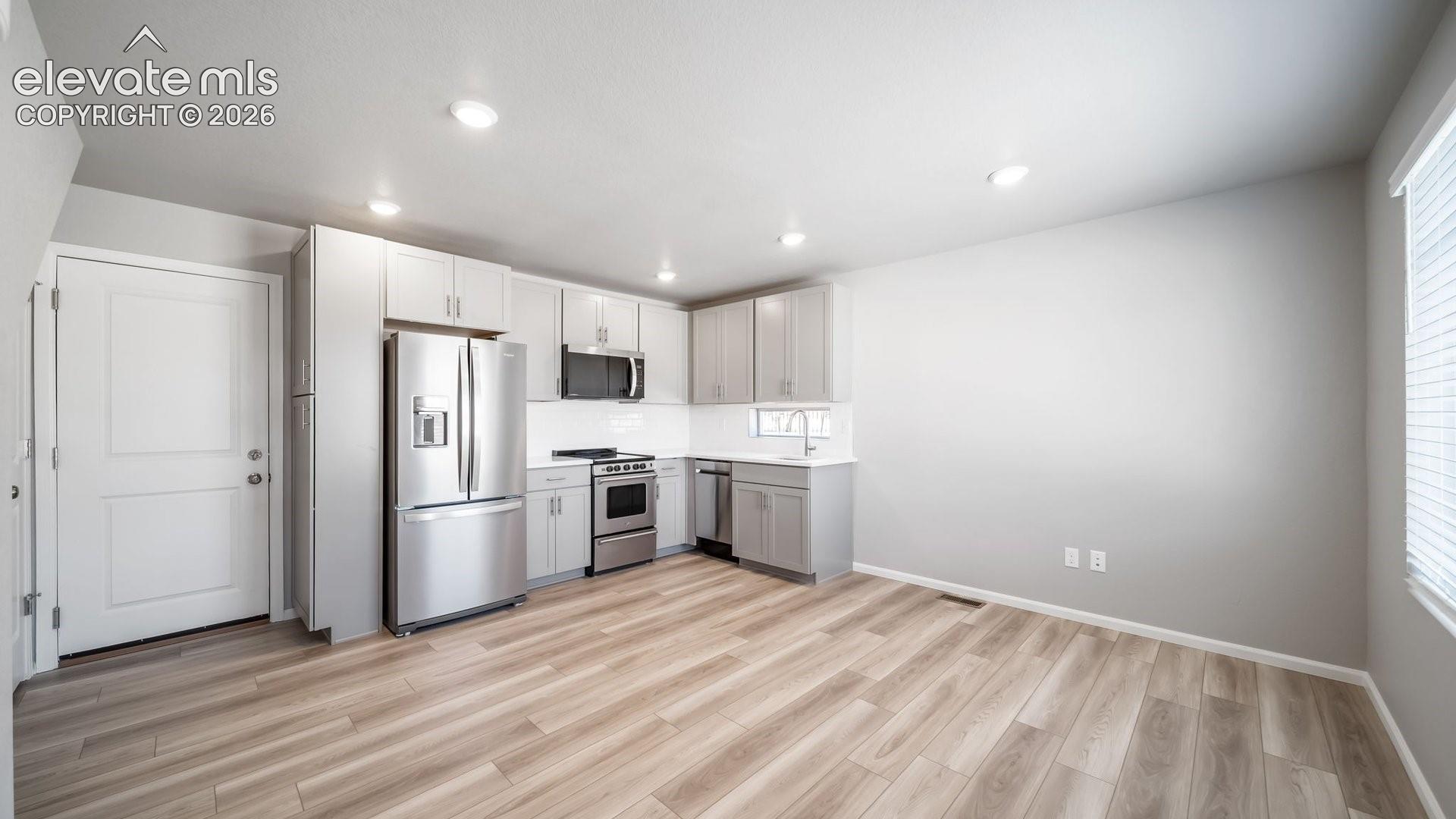 Kitchen featuring light-toned cabinetry, stainless steel appliances, wood-finish flooring, and recessed lighting
*photos of a model home*