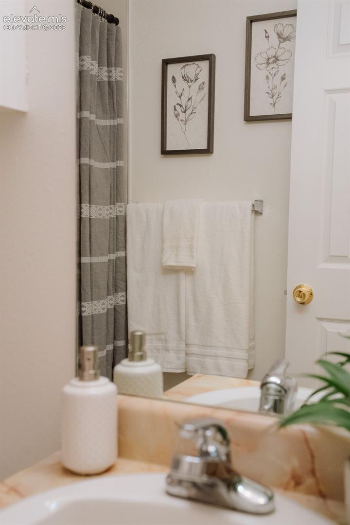 Stone-finish countertop featuring an integrated sink with a polished chrome faucet, paired with a wall-mounted metal towel bar