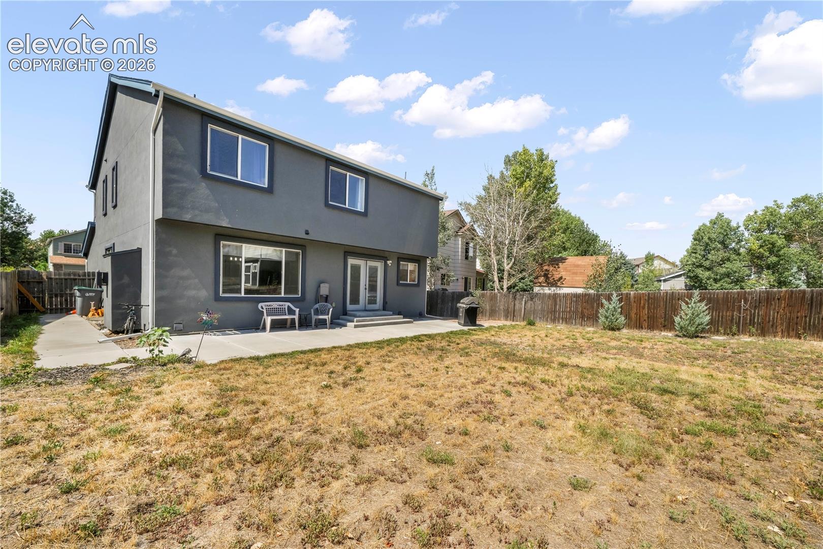 Back of home with large backyard patio, multiple levels, basketball goal and shed for storage