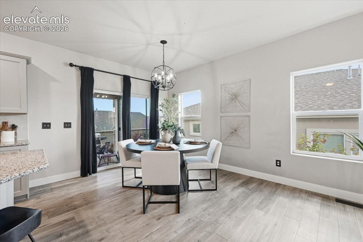 Wood-finish flooring, sliding glass door, pendant light fixture, multiple windows, and a built-in countertop