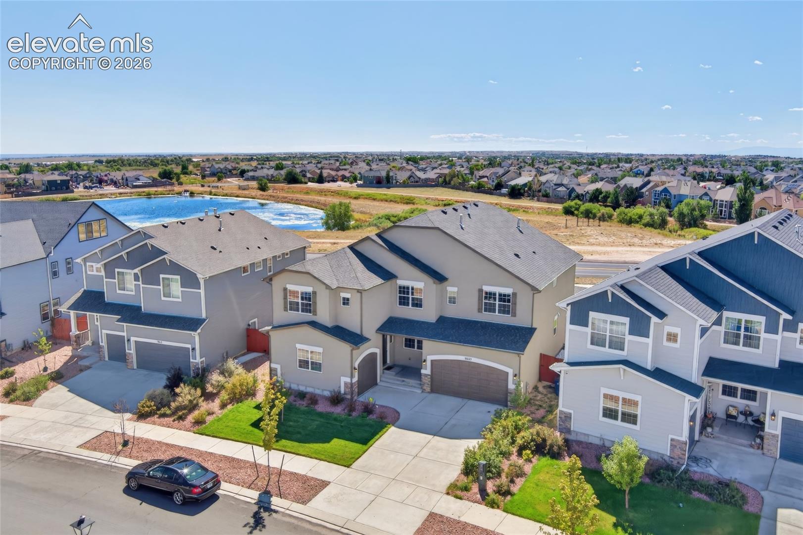Two-story residence with a two-car garage, mature landscaping, and an adjacent community lake