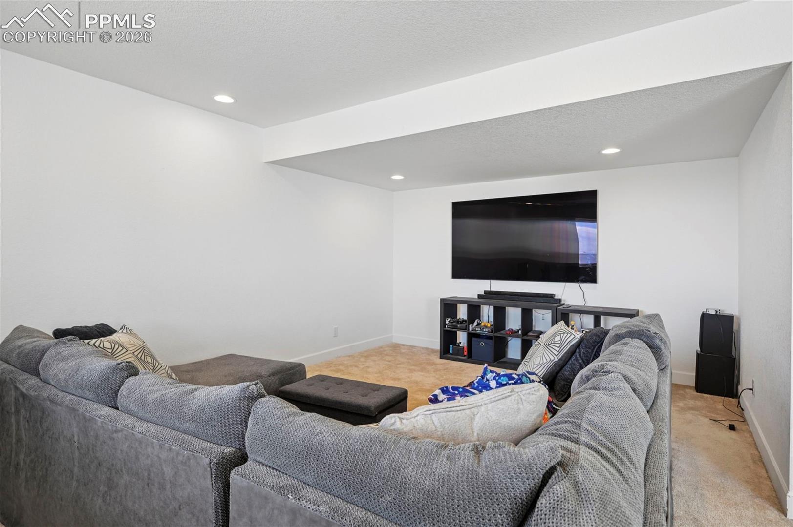 Recessed lighting illuminates a spacious room featuring a wall-mounted display above modular shelving