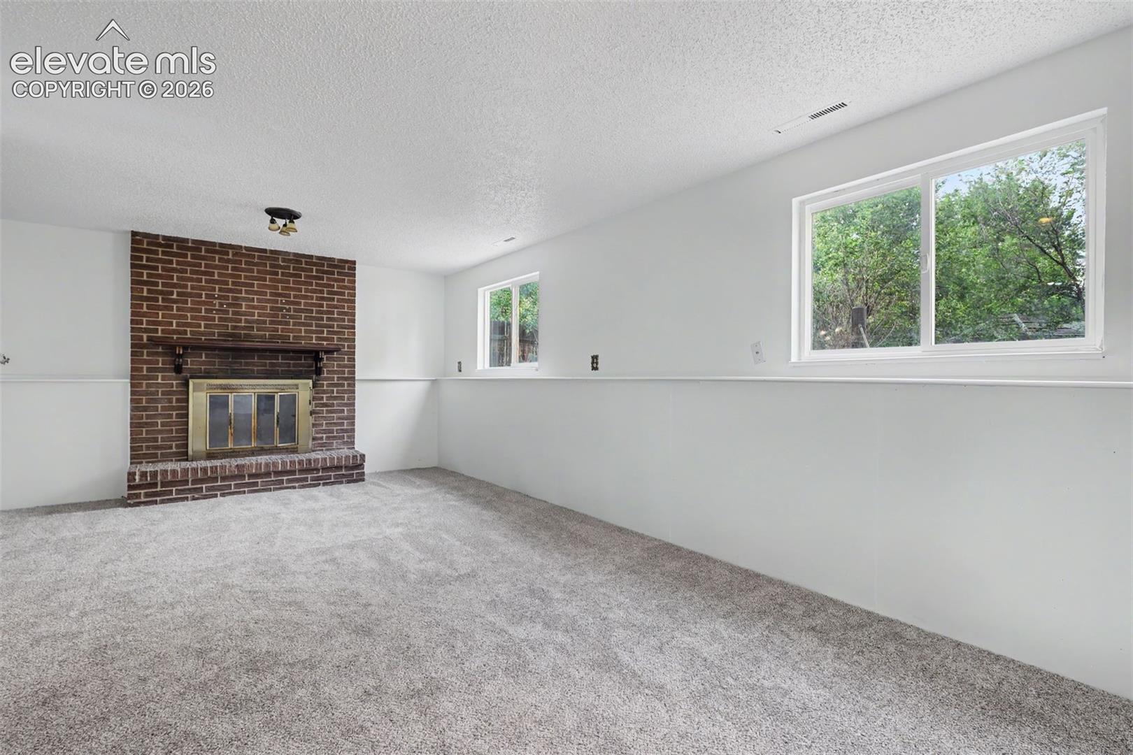Spacious lower level family room with wood burning brick fireplace.