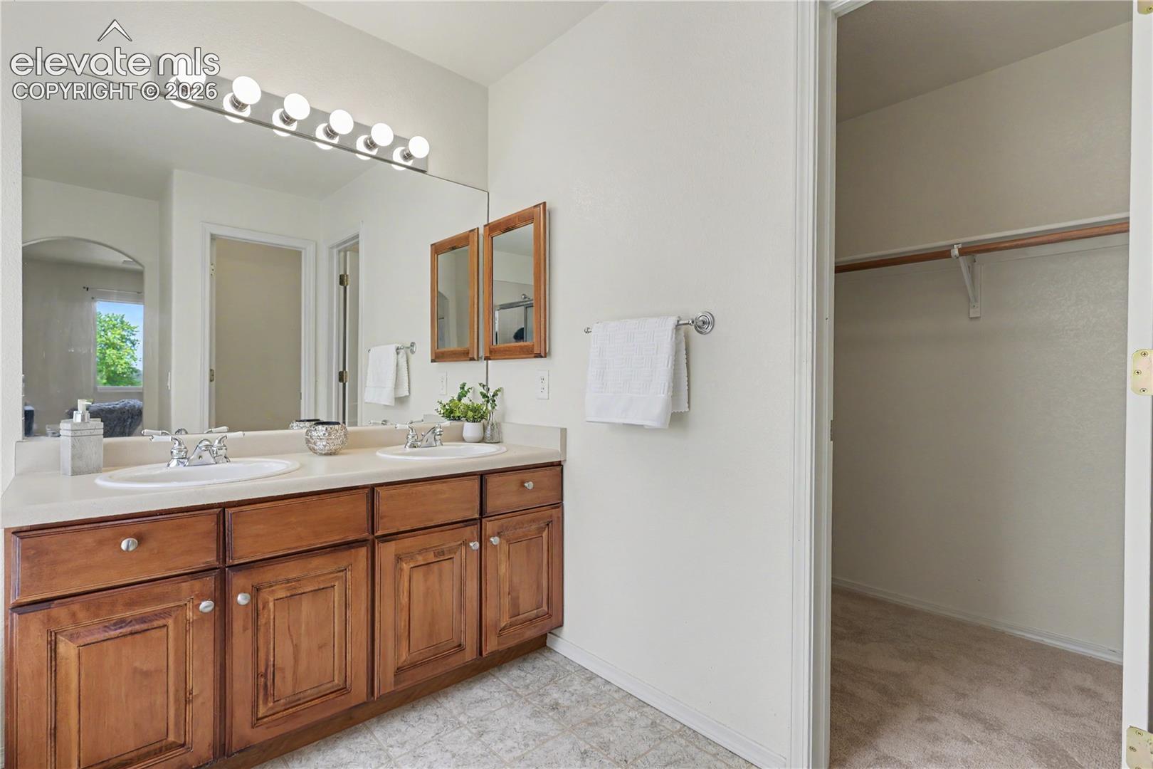Double vanity with integrated sinks and a light-toned countertop, set against a large mirror with a six-bulb vanity light fixture