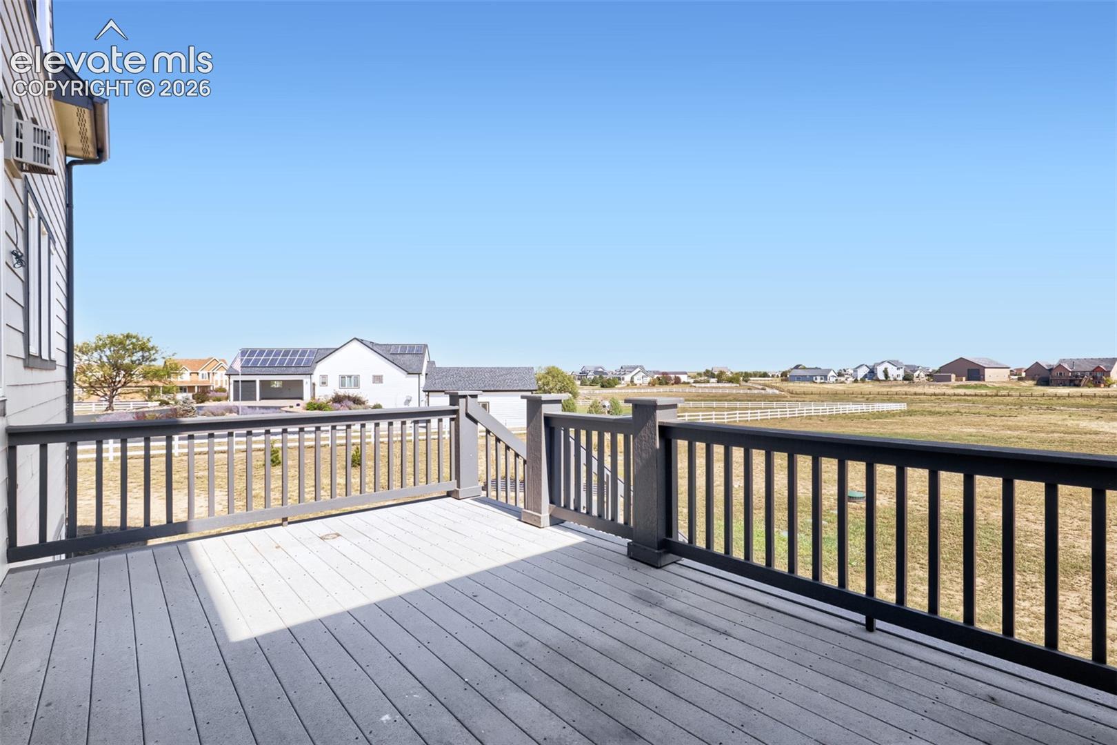 Conveniently located right off the kitchen, this spacious composite deck features durable grey decking, dark railings, and direct stairs to the backyard. Ideal for grilling and outdoor dining while enjoying wide-open, panoramic countryside views under big blue skies.
