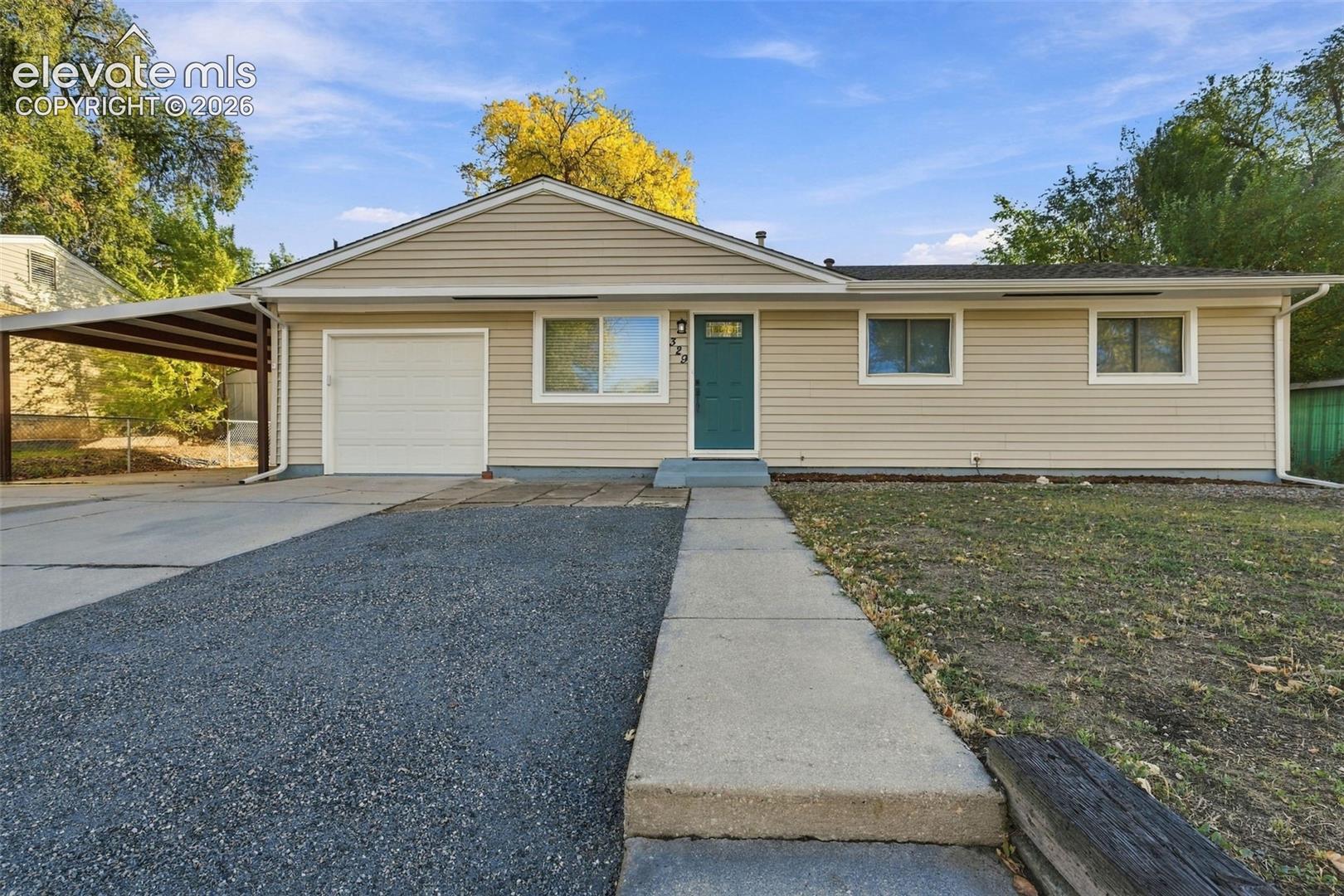 Ranch-style exterior featuring light-toned horizontal siding, a covered carport, and a concrete walkway