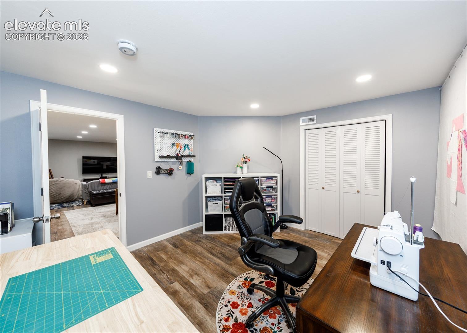 Dedicated creative workspace featuring recessed lighting, wood-finish flooring, and built-in shelving with organizational cubbies
