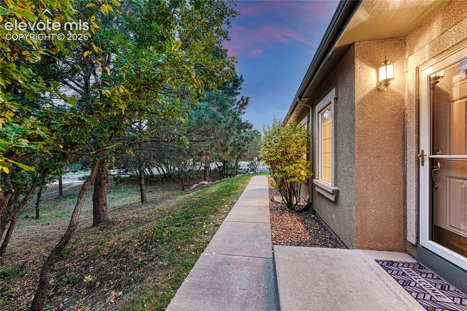 The inviting covered front porch with a storm door welcomes guests into a tranquil environment adjacent to open scrub oak parkland
