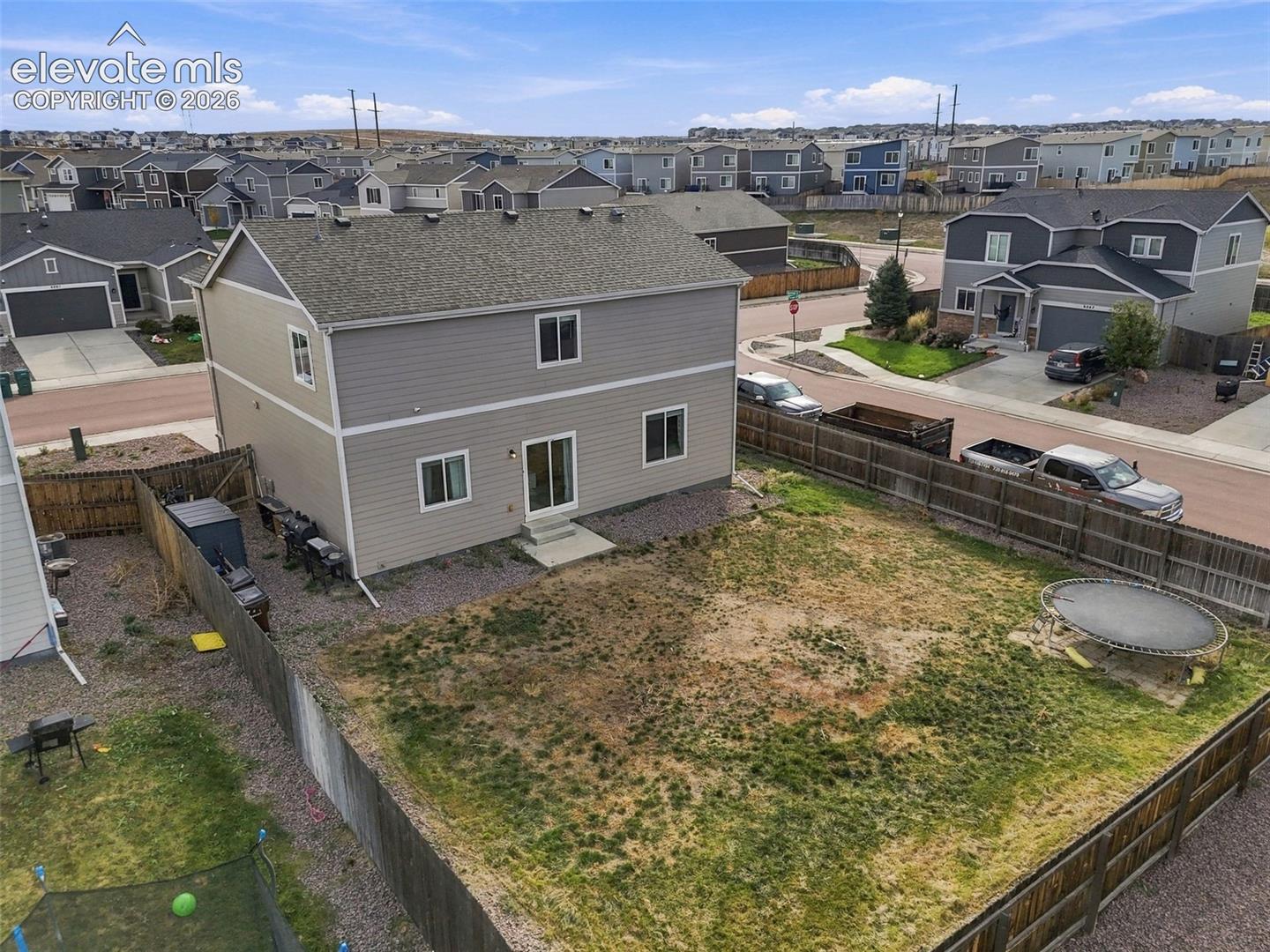 Two-story residence featuring grey horizontal siding, asphalt shingle roofing, and a fenced backyard