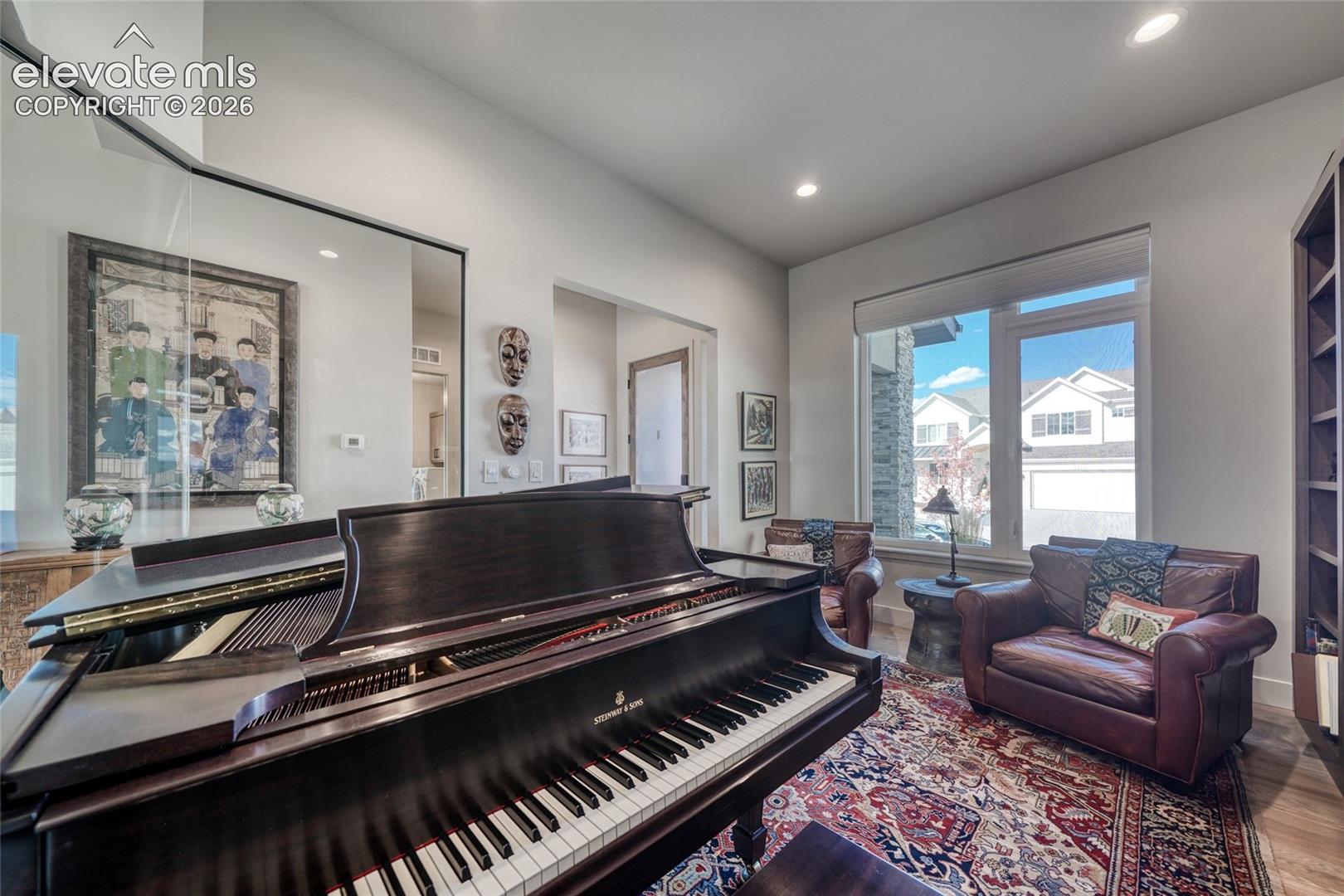 Room featuring high ceilings, floor-to-ceiling mirror, tall built-in shelving unit, and large windows with integrated shades