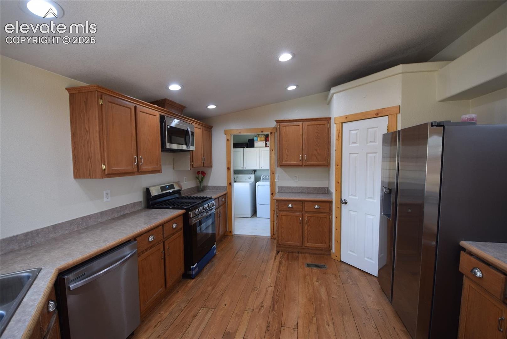 Kitchen featuring wood-finish flooring, recessed lighting, wood cabinetry, stainless steel appliances, and laminate countertops