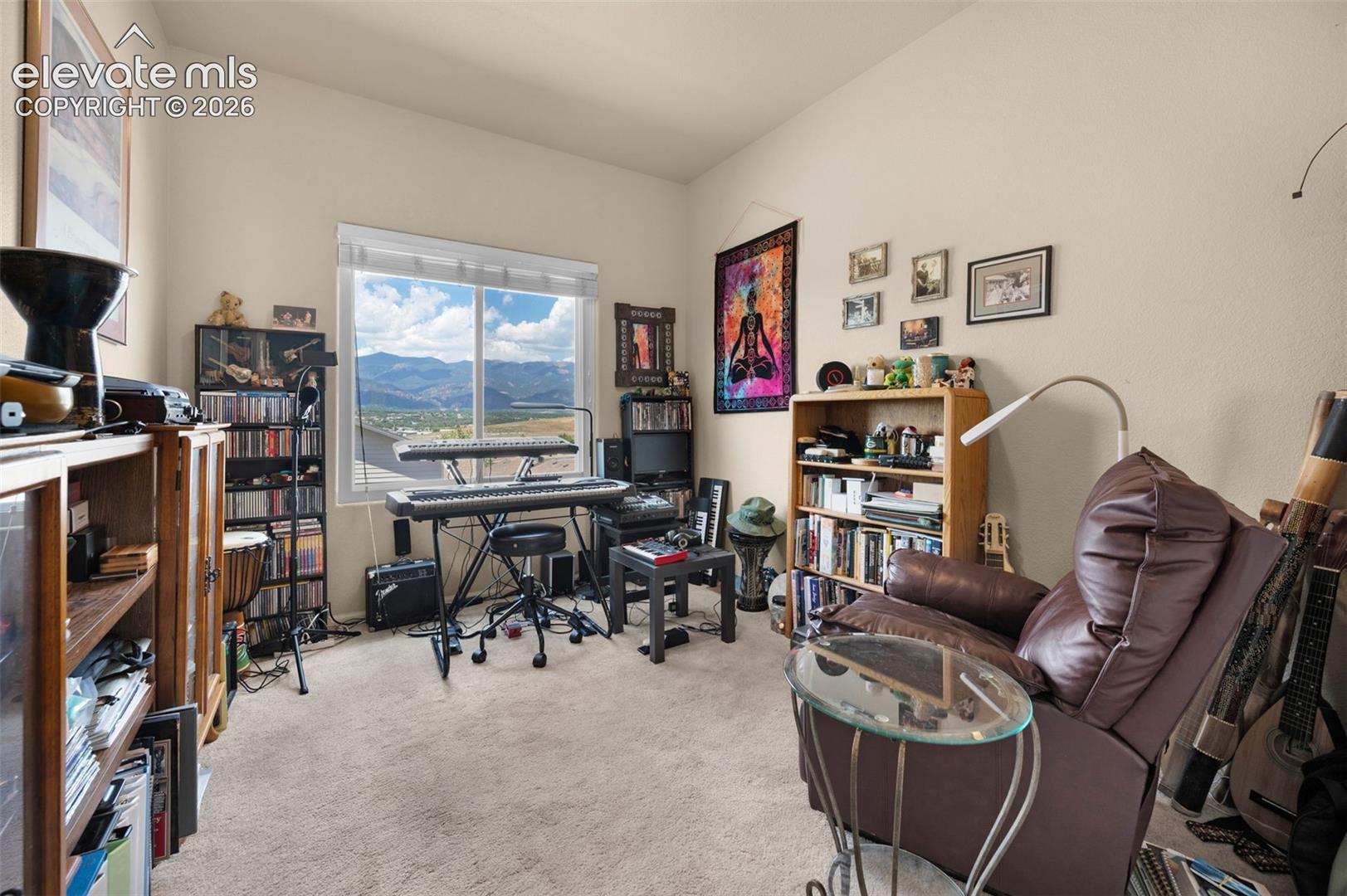 Bedroom #3 being used as a music room. Light-colored walls and carpeting create a neutral palette in this room, featuring a large window with mountain scenery