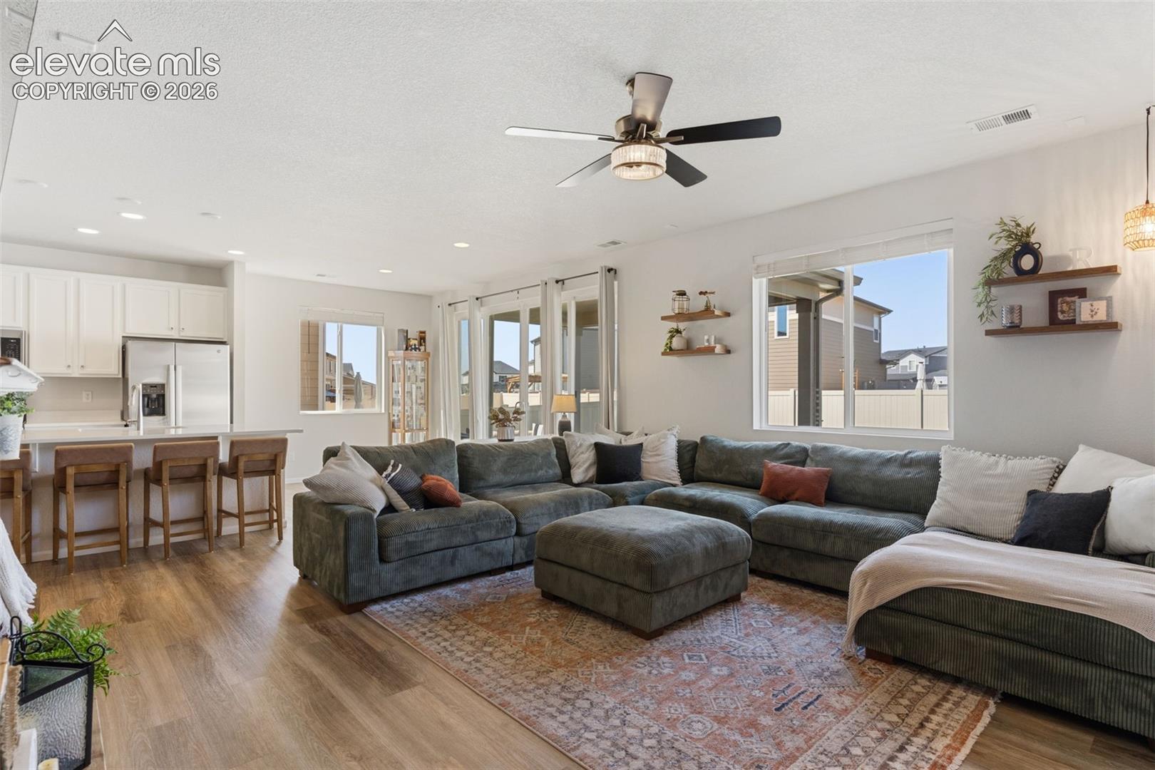 Open-concept living area featuring wood-finish flooring, recessed lighting, and a ceiling fan
