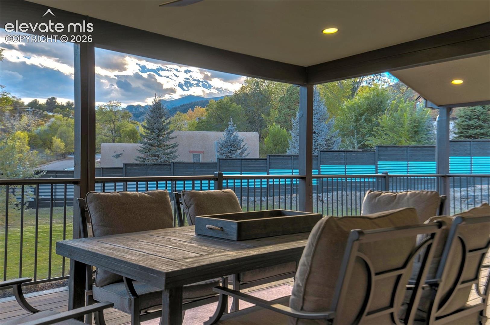 Covered patio featuring recessed lighting, metal railing, and mountain backdrop