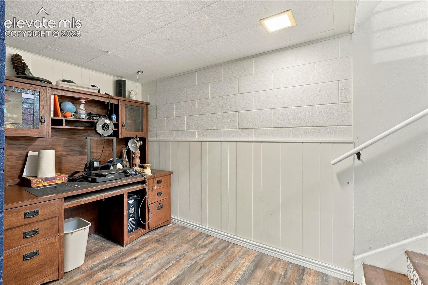 Built-in wooden cabinetry with integrated desk space, wood-finish flooring, painted masonry walls, and recessed lighting