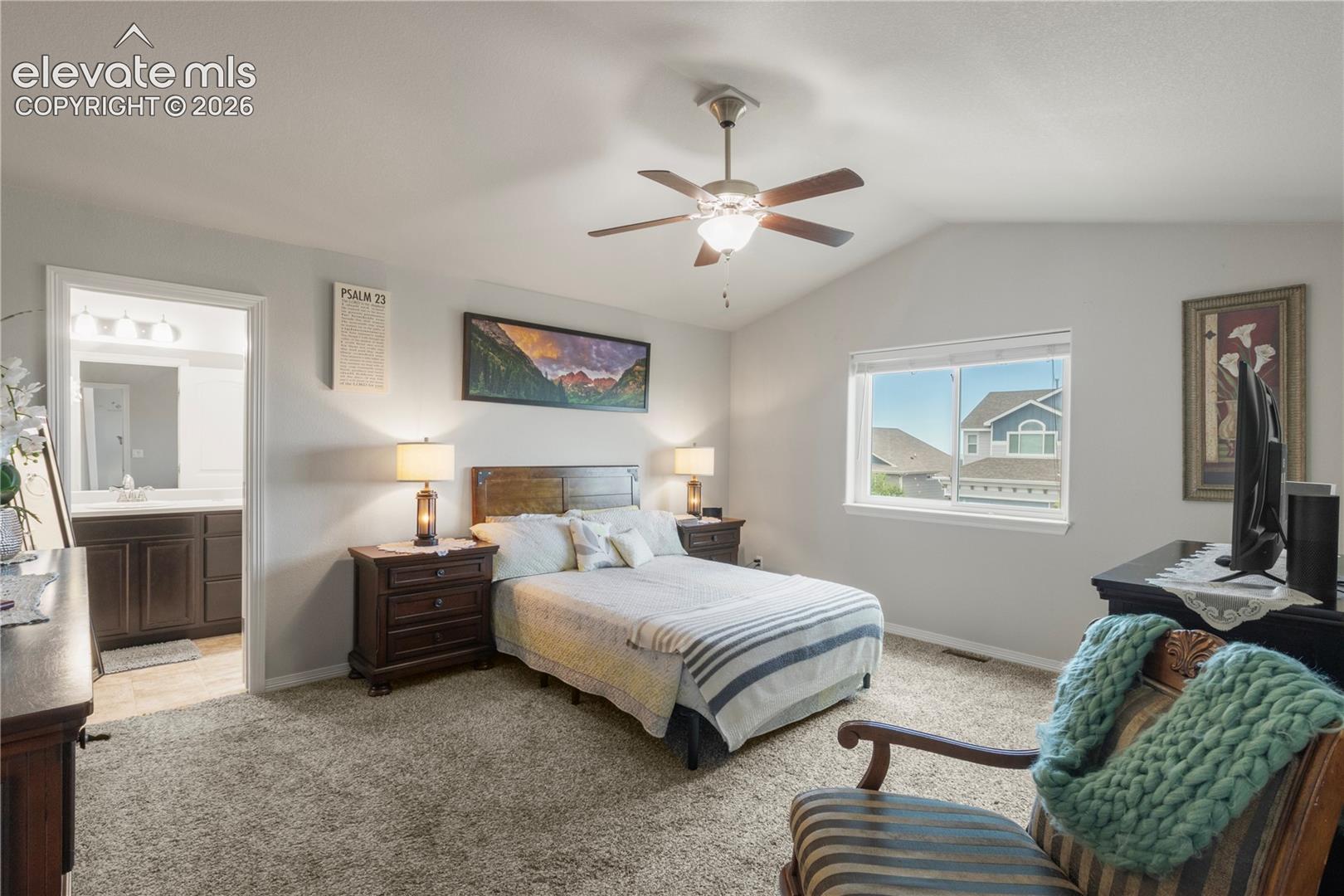 Vaulted ceiling with ceiling fan, large window, and broadloom carpeting