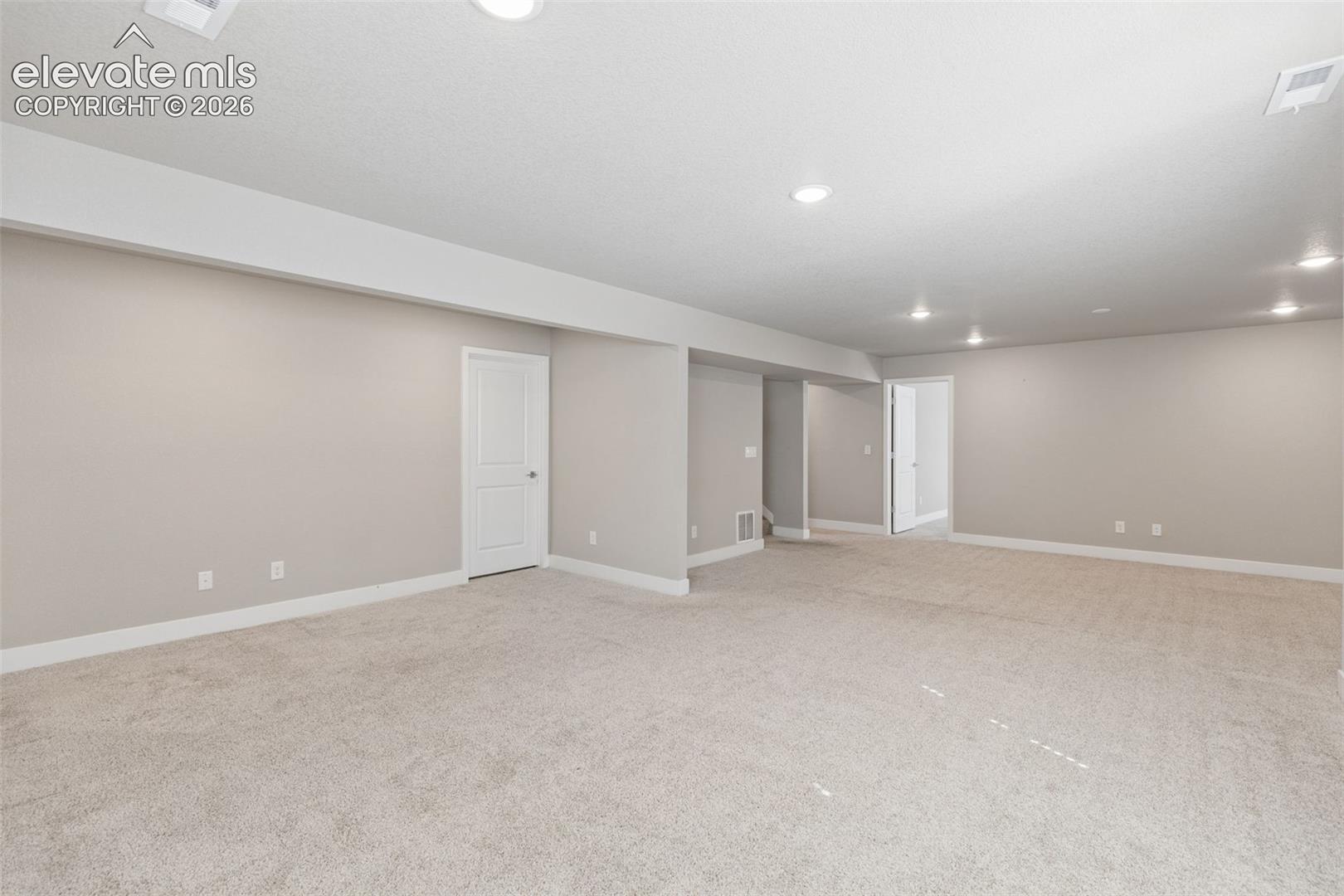 Neutral-toned interior space featuring wall-to-wall carpeting, recessed ceiling lighting, and solid-core paneled interior doors