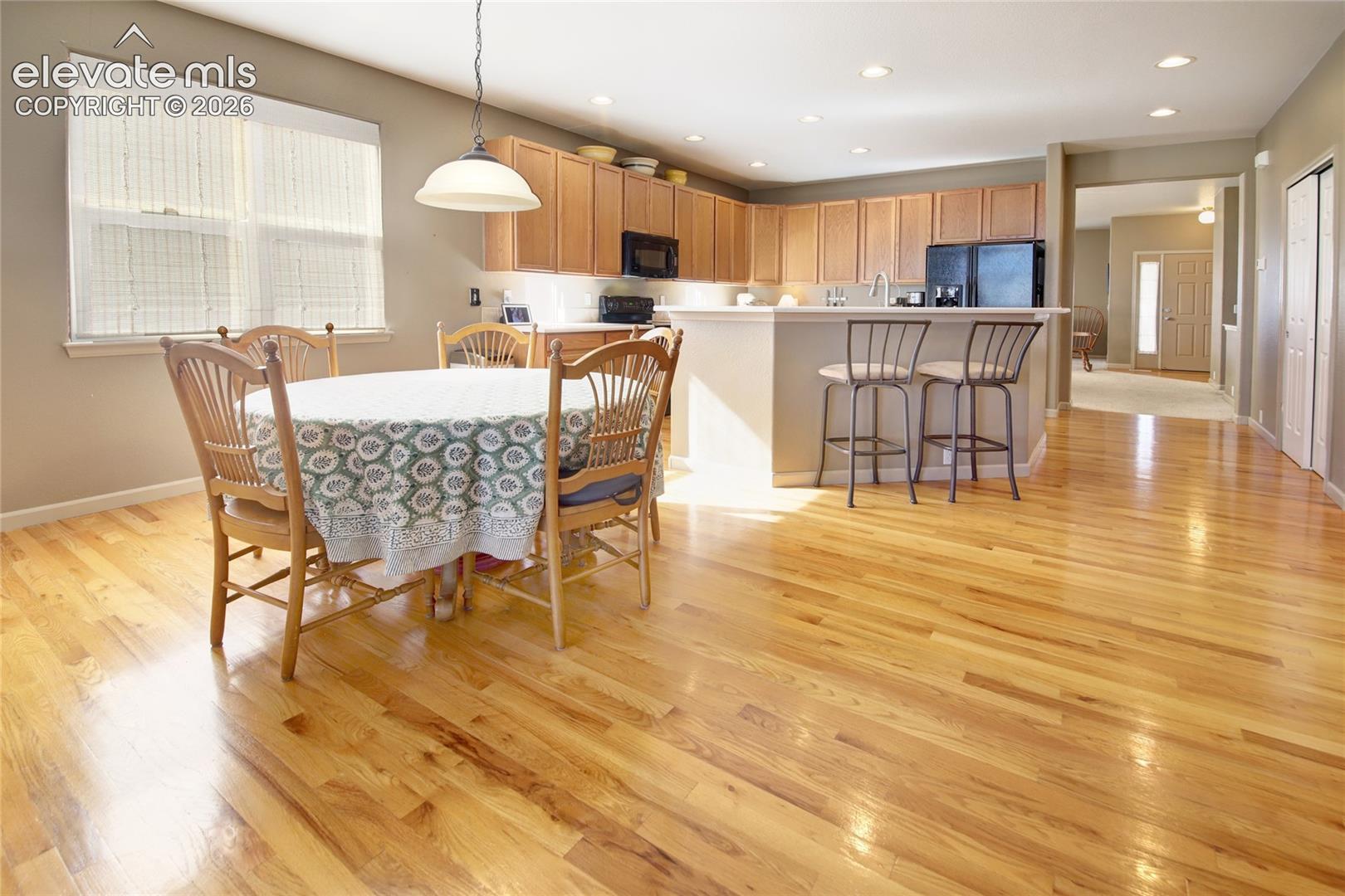 Kitchen featuring wood-finish flooring, recessed lighting, wood cabinetry, and a peninsula with counter seating