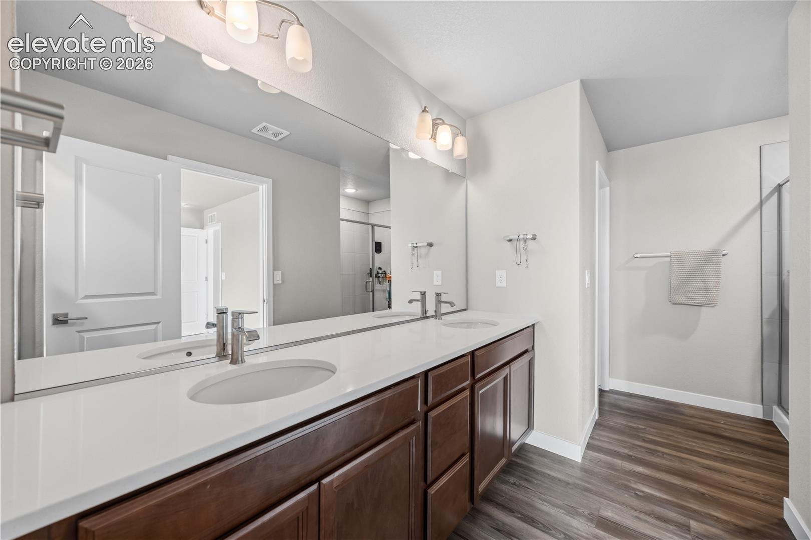 The Primary Bathroom features an extended vanity with dual sinks, mirror, and enclosed tiled shower.