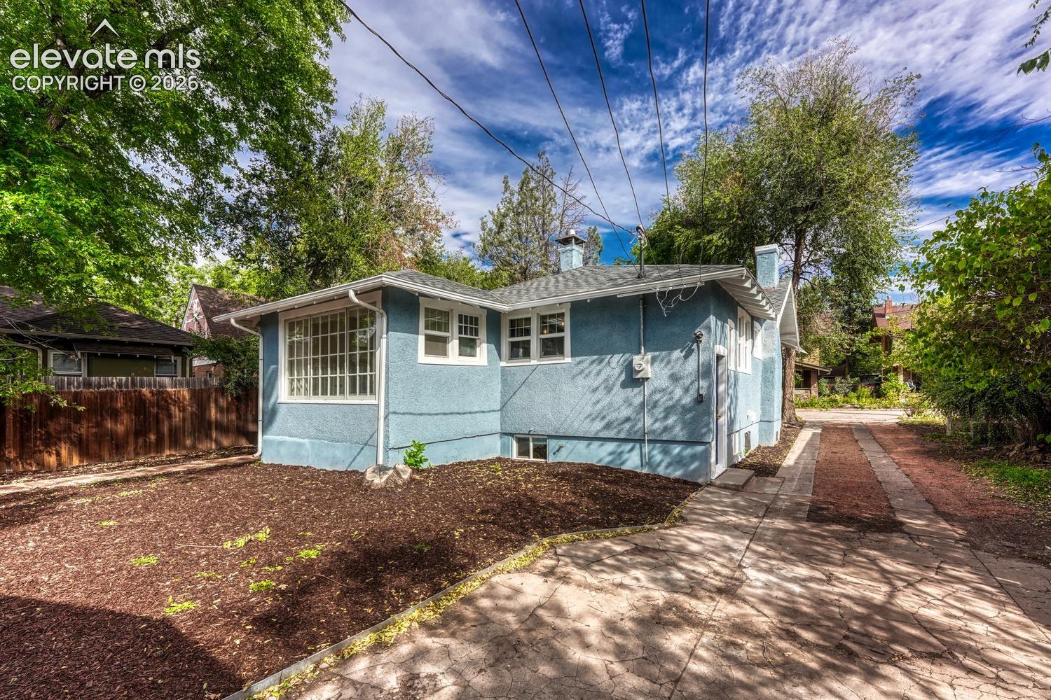 Blue stucco exterior with white trim windows and a light gray shingle roof
