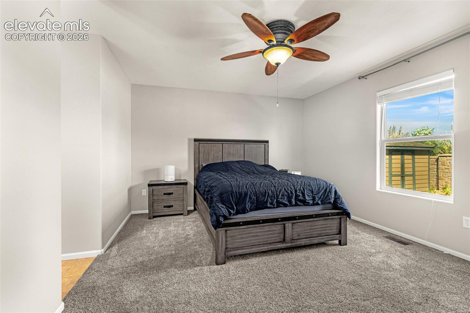 Carpeted room with a ceiling fan light fixture and a window with blinds