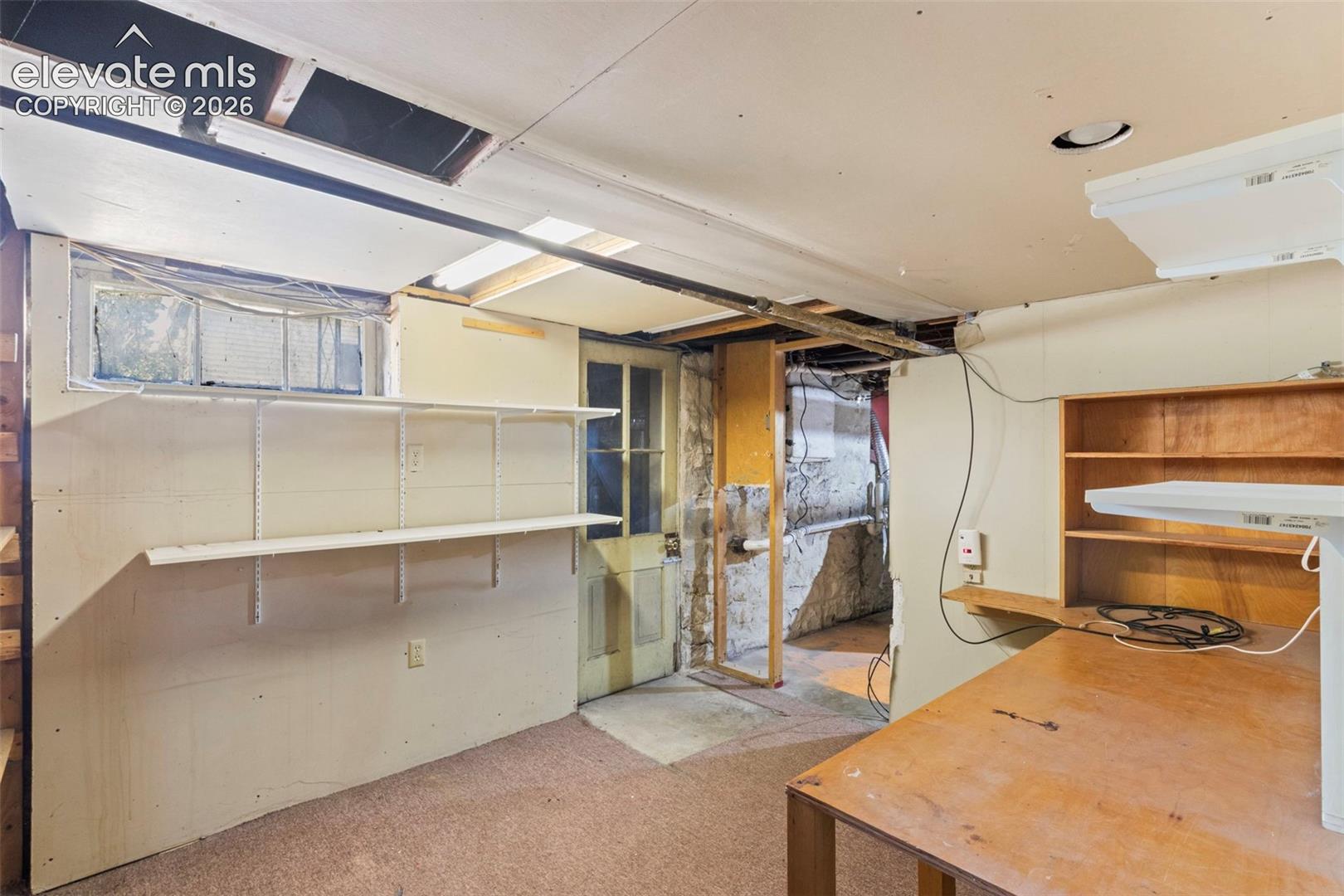 Basement with desk, storage shelves and walk out.