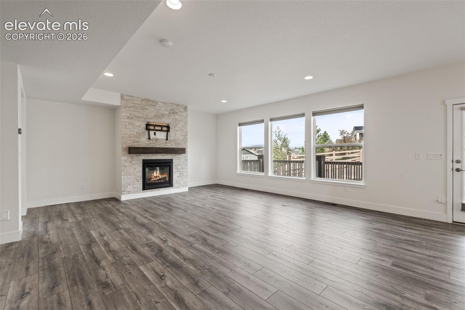 Contemporary fireplace with a stacked stone surround and wood mantel