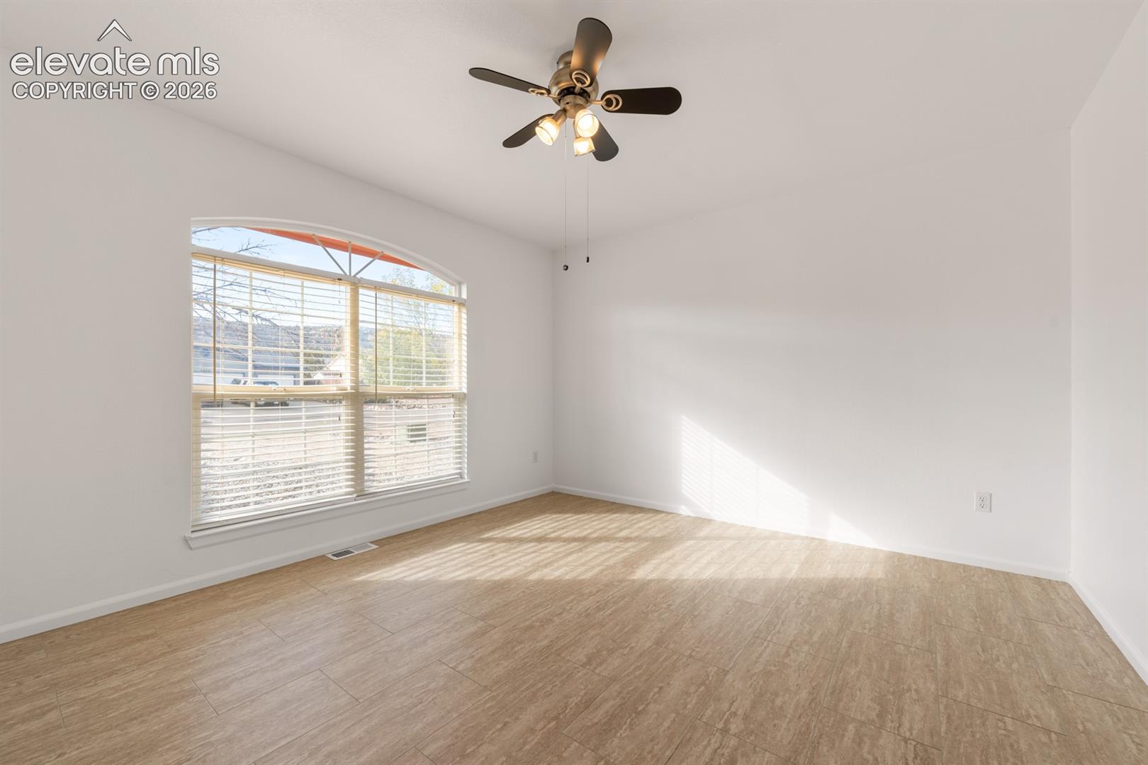 Interior space featuring wood-finish flooring, an arched window, and a multi-light ceiling fan