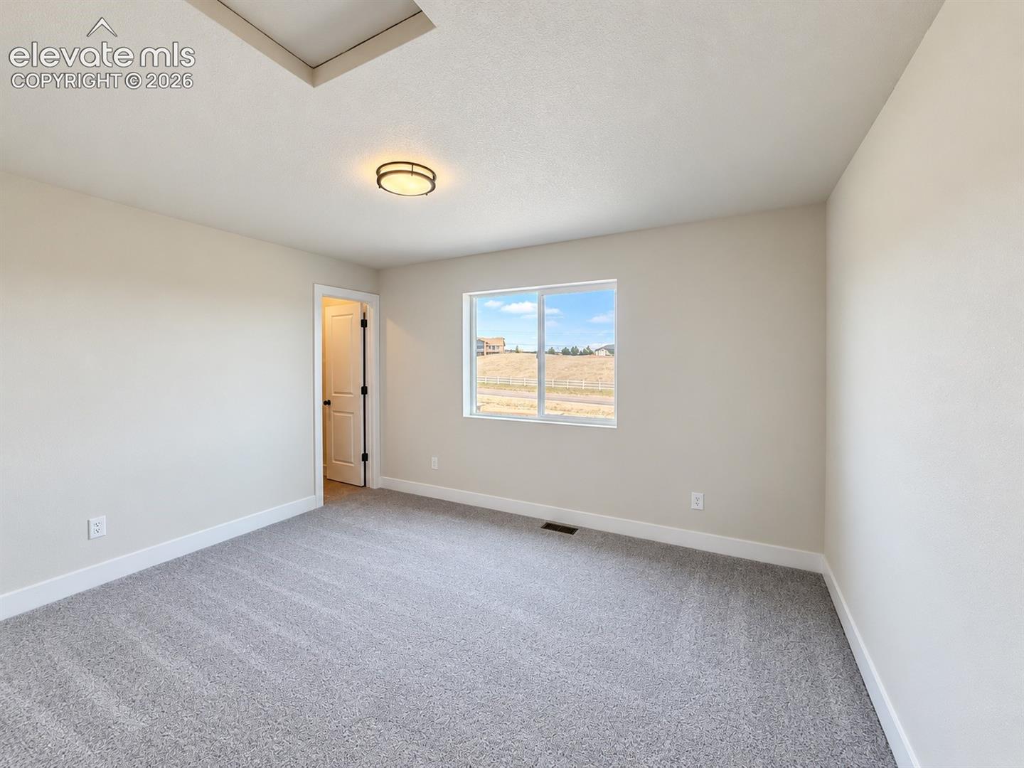 Neutral-toned interior featuring wall-to-wall carpeting, a flush-mount ceiling light fixture, and a single-pane sliding window