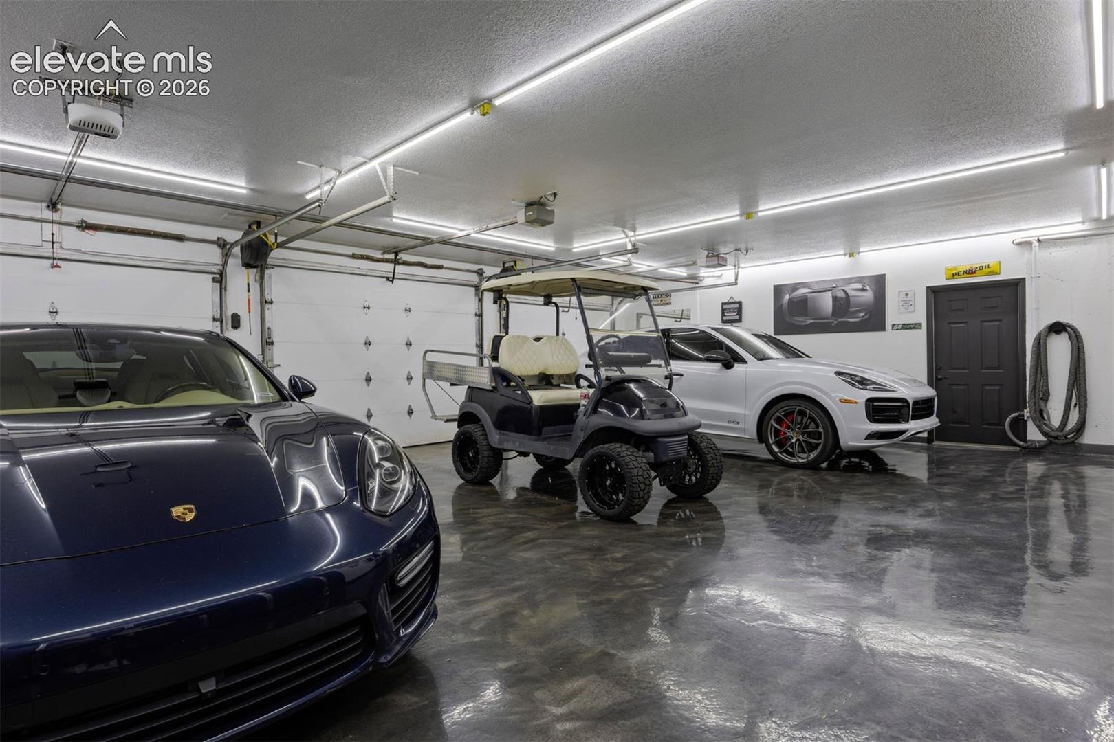 Oversized 4-car garage with polyaspartic floors, LED strip lighting, four separate insulated garage doors, and central drain in all bays.