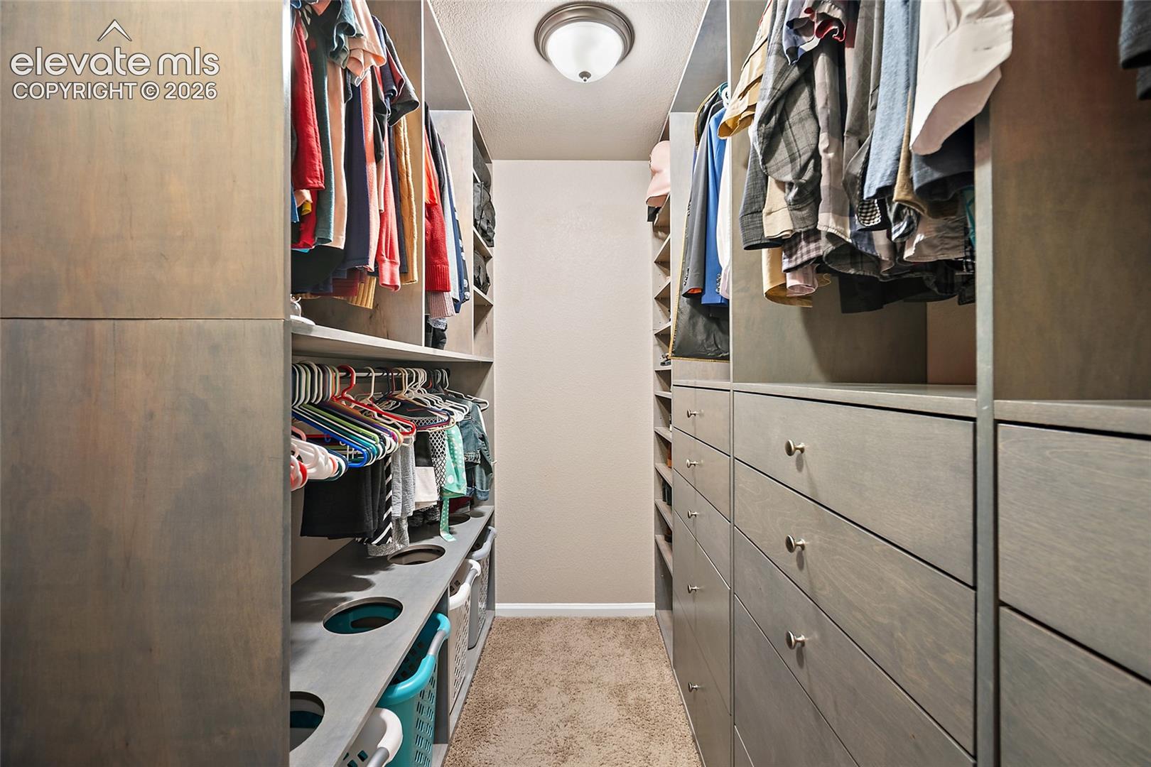 Custom primary bedroom closet featuring built-in cabinetry.