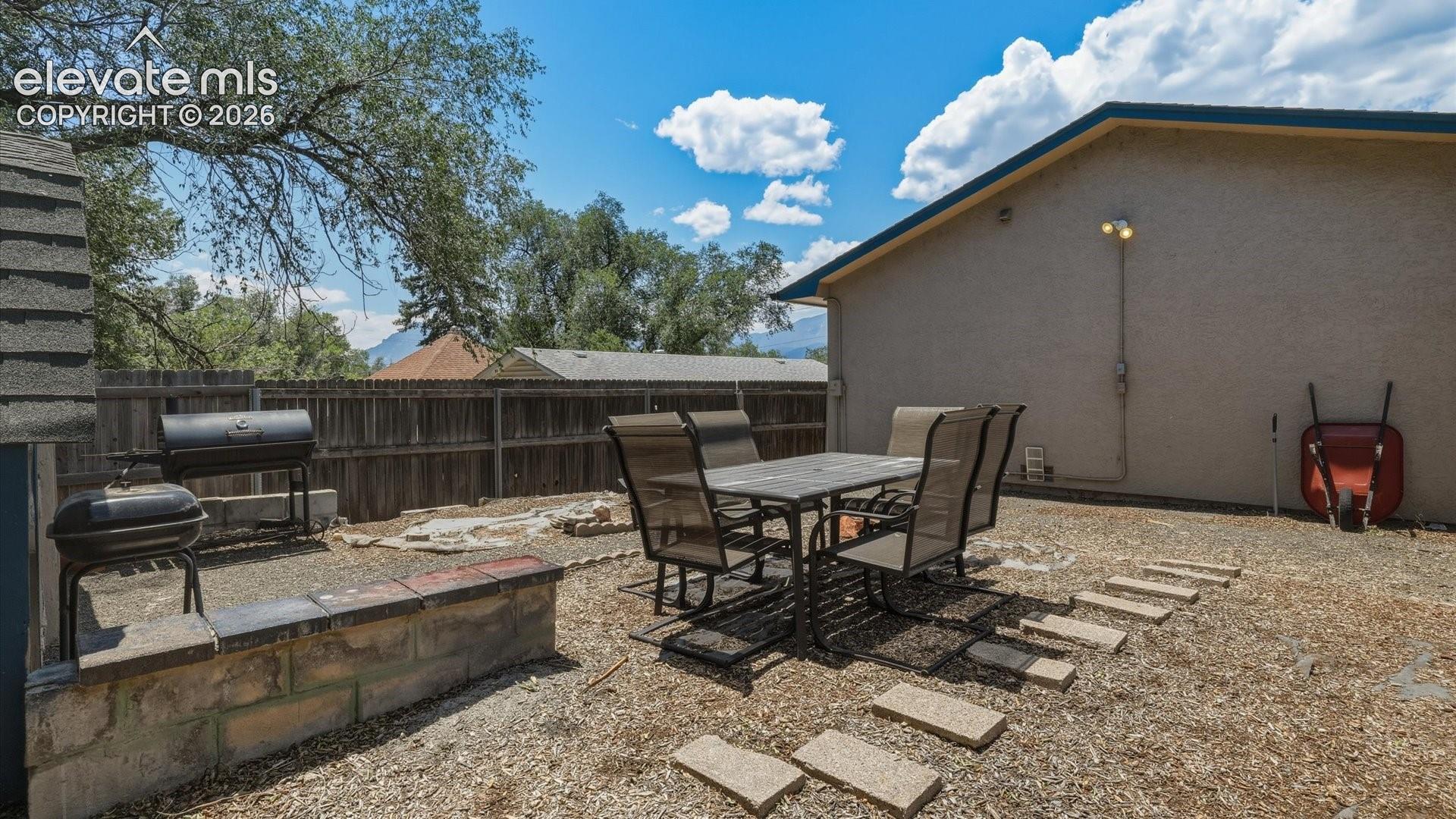 Fenced level backyard with areas for outdoor dining and entertaining.