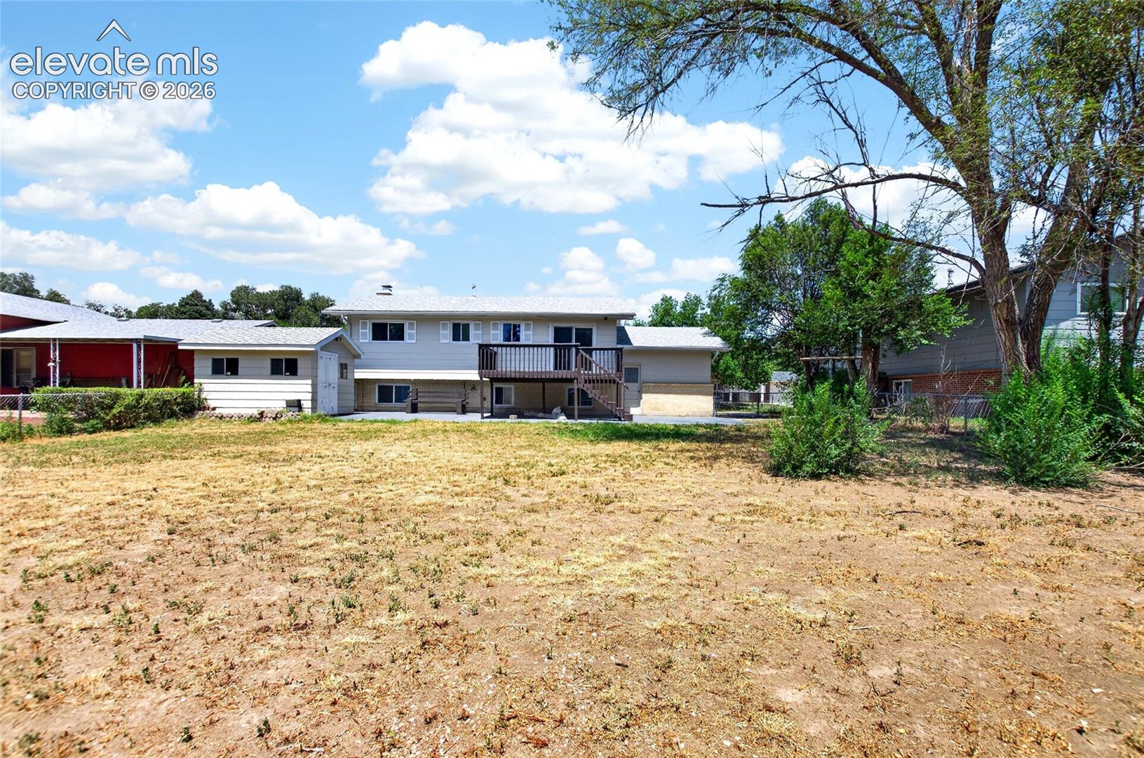 Spacious backyard area featuring a multi-level residence with an upper-level deck and lower-level patio
