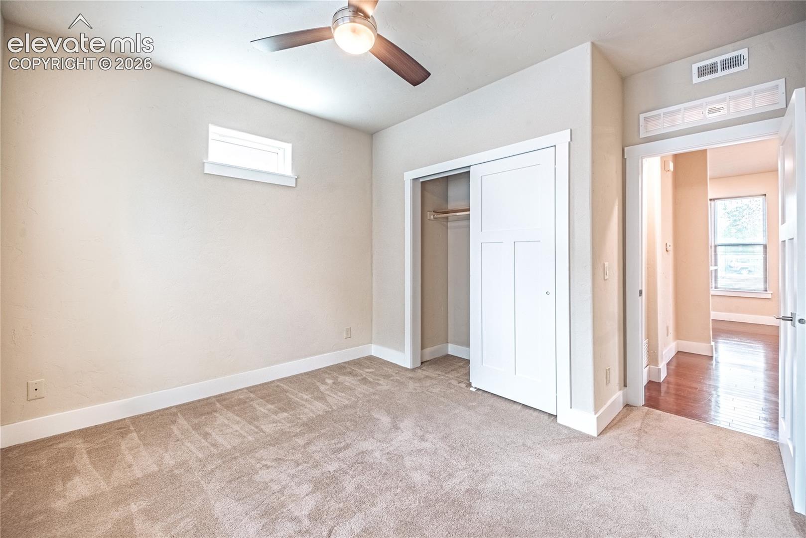 Carpeted room with a ceiling fan, a high-set window, and a white sliding closet door