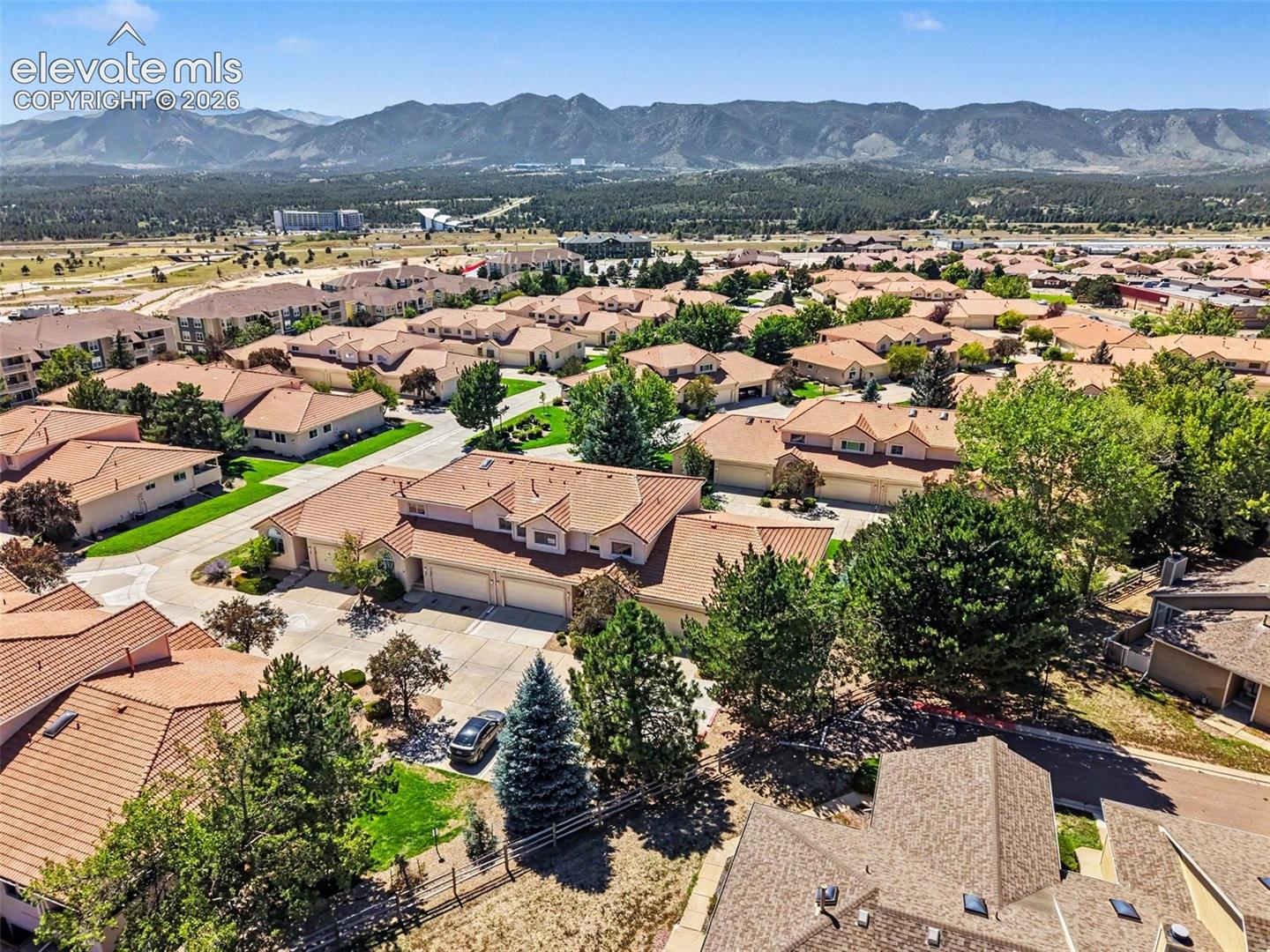 Expansive residential community with terracotta-style roofs, mature landscaping, and mountain backdrop