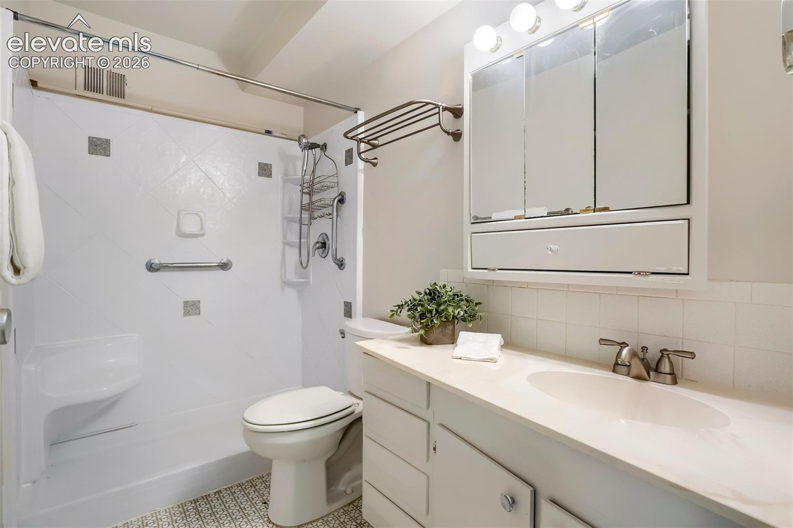 Bathroom featuring a white vanity with an integrated sink, brushed nickel faucet, and a large mirrored medicine cabinet with integrated lighting