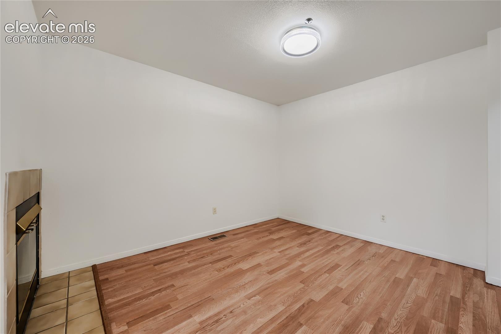 Bright, open room with warm wood-finish flooring throughout, white walls, and recessed ceiling lighting