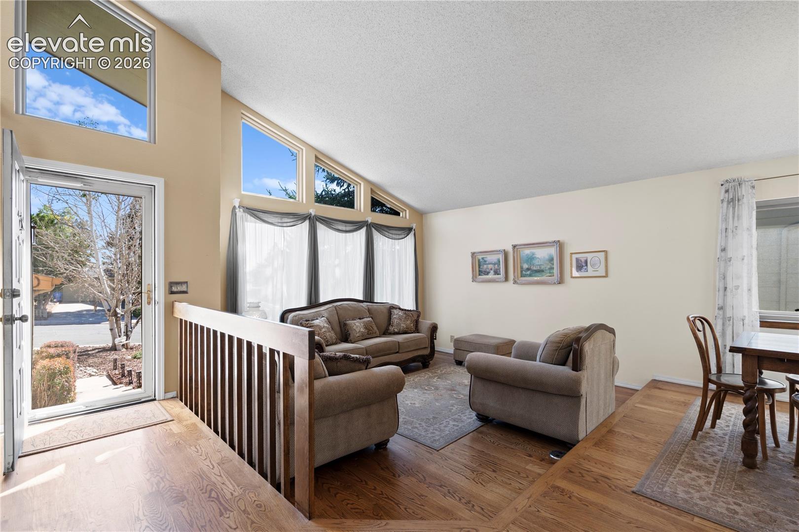 Vaulted ceilings with clerestory windows, wood-finish flooring, and a multi-pane front entry door