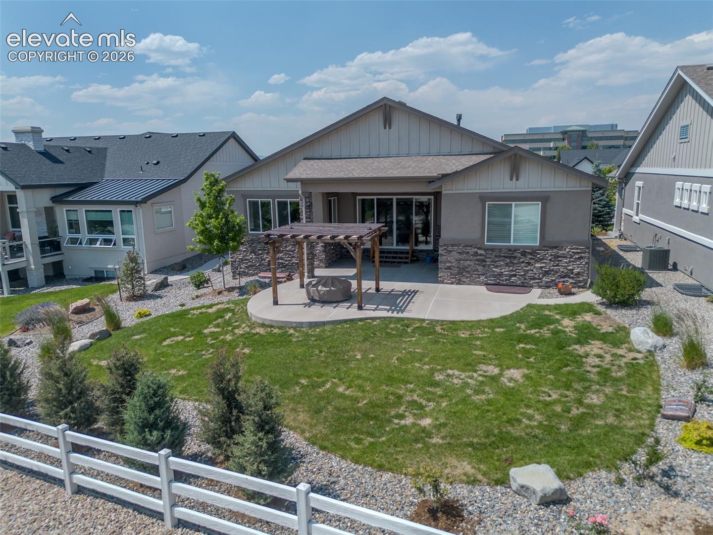 Rear exterior featuring a concrete patio, wood pergola, and a built-in fire pit