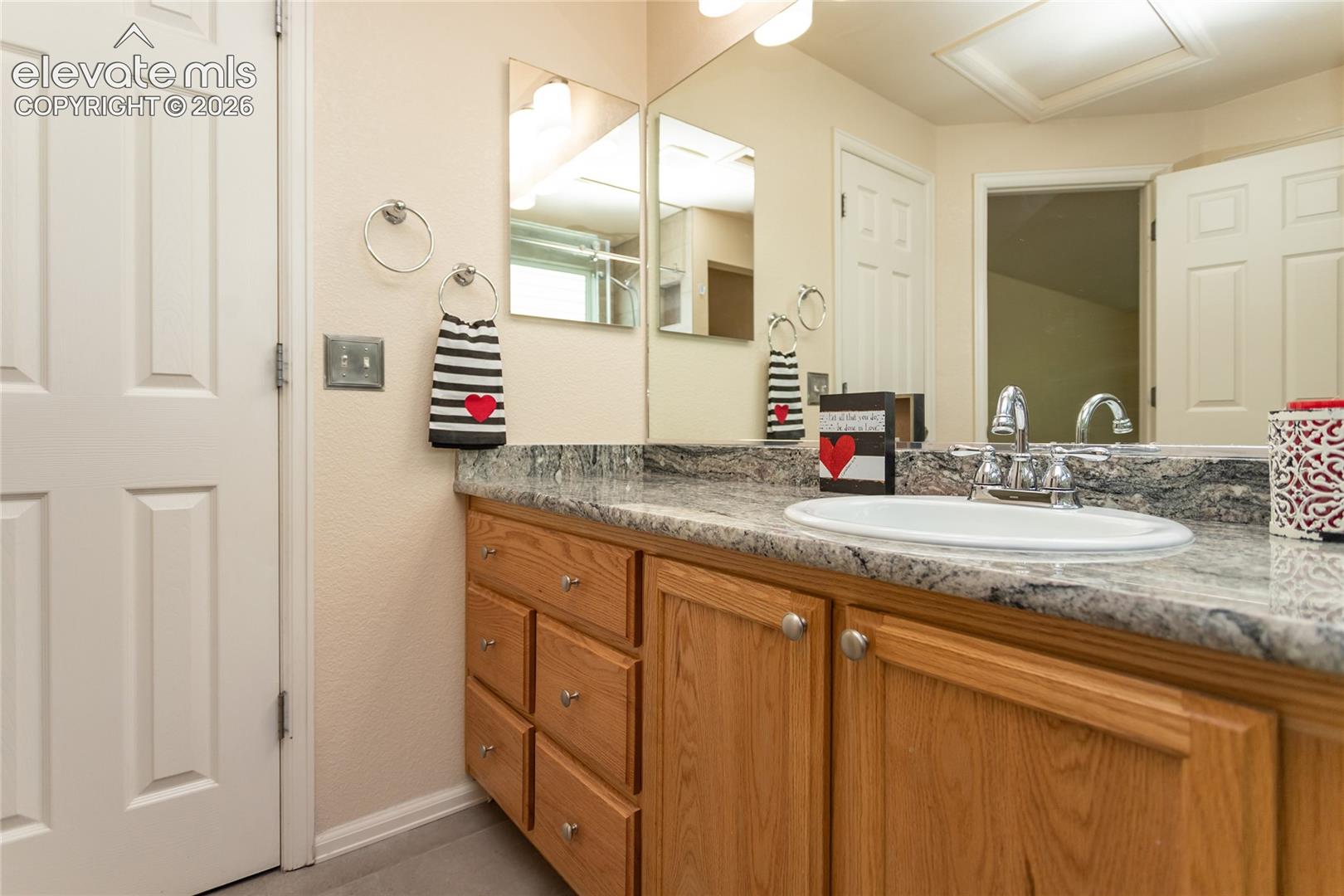 Custom made wood vanity featuring granite countertop.  Door to the left is to the walk-in closet.