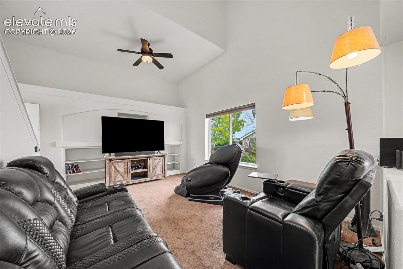 Vaulted ceiling, built-in shelving, and ceiling fan