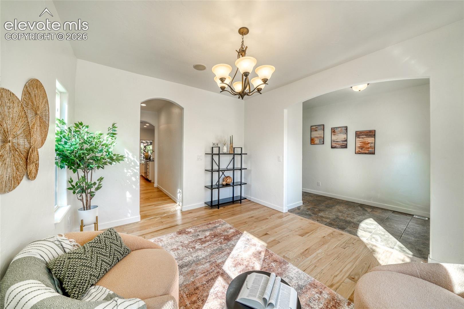 Archways define separate spaces with wood-finish flooring and a multi-light chandelier