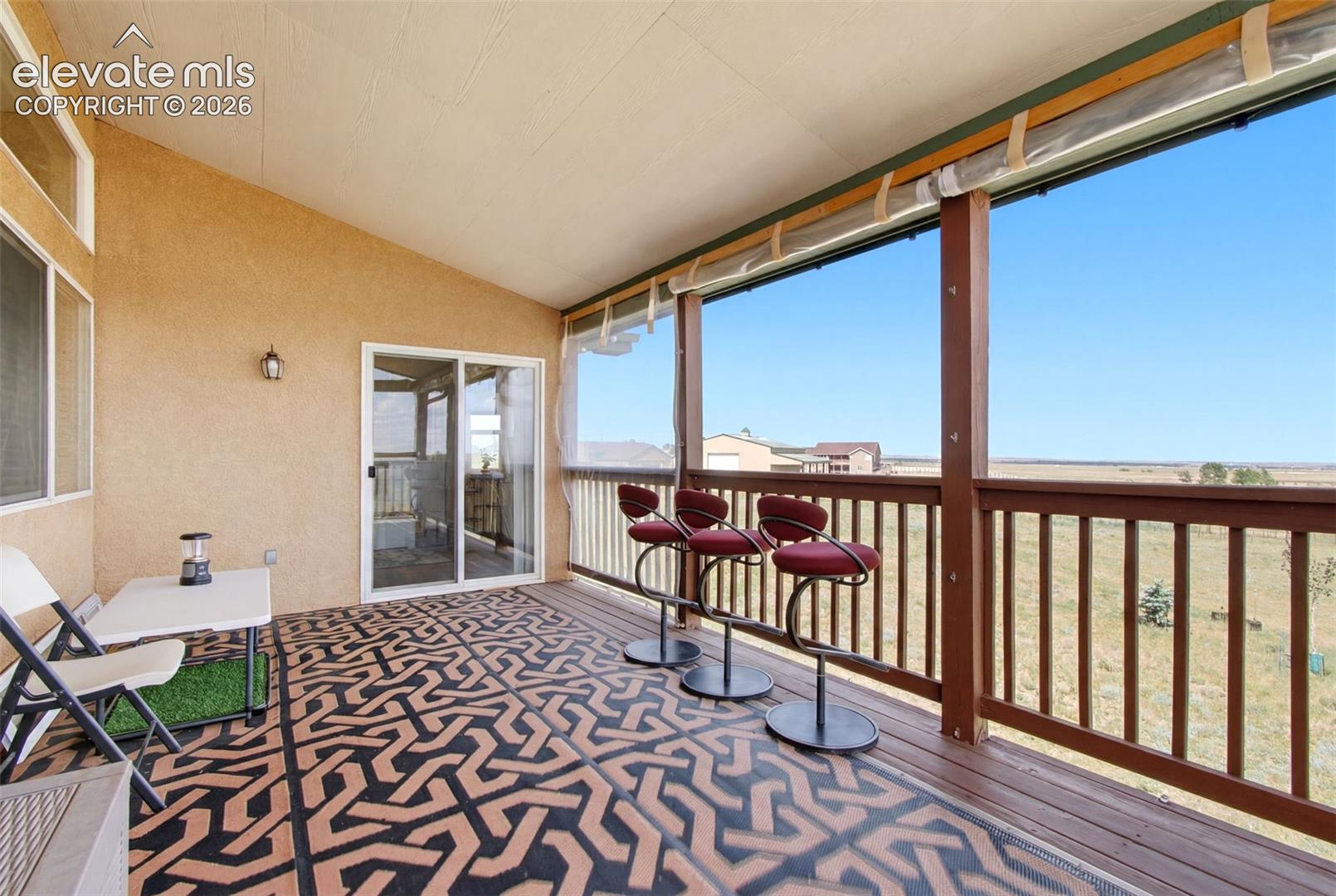 Elevated deck featuring geometric patterned flooring, wood-finish railings, and expansive open-air design with clear sightlines across the landscape