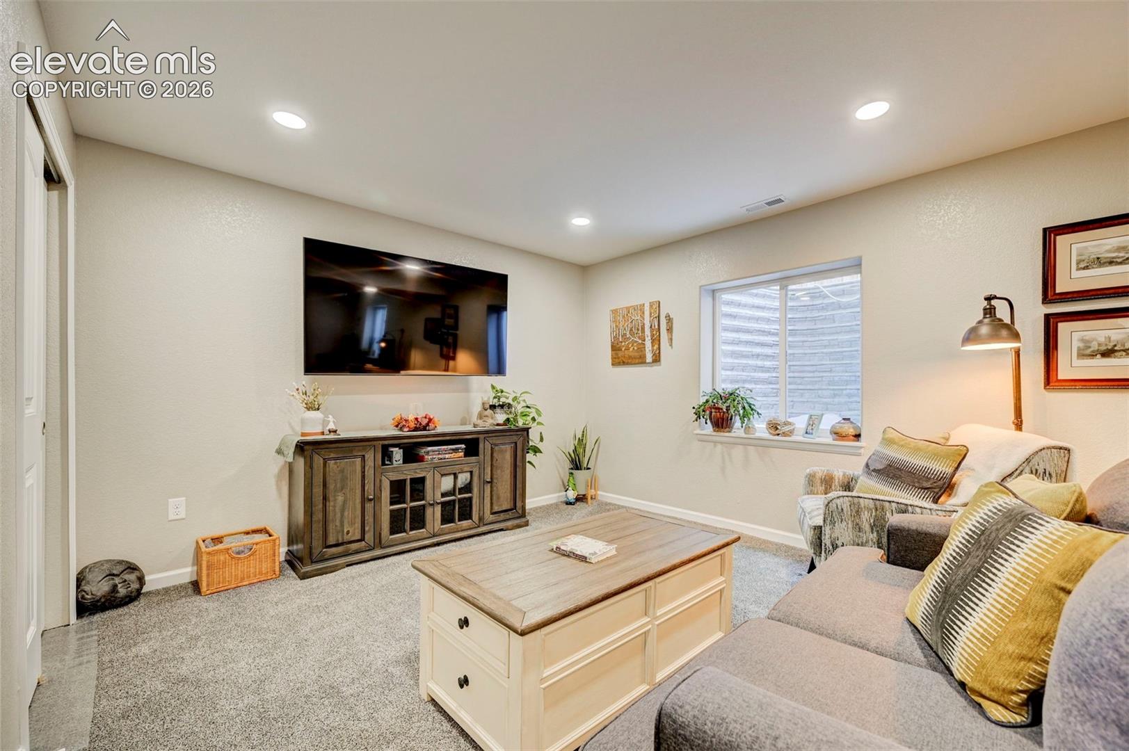 Neutral wall tones, recessed lighting, and a garden-level window with a window well