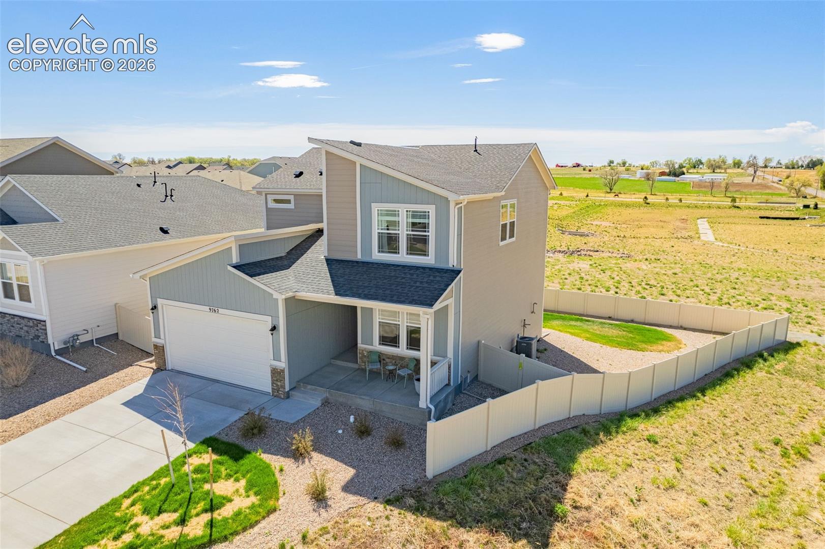 Modern architectural style, two-story residence with a covered front porch, attached garage, and a fenced backyard