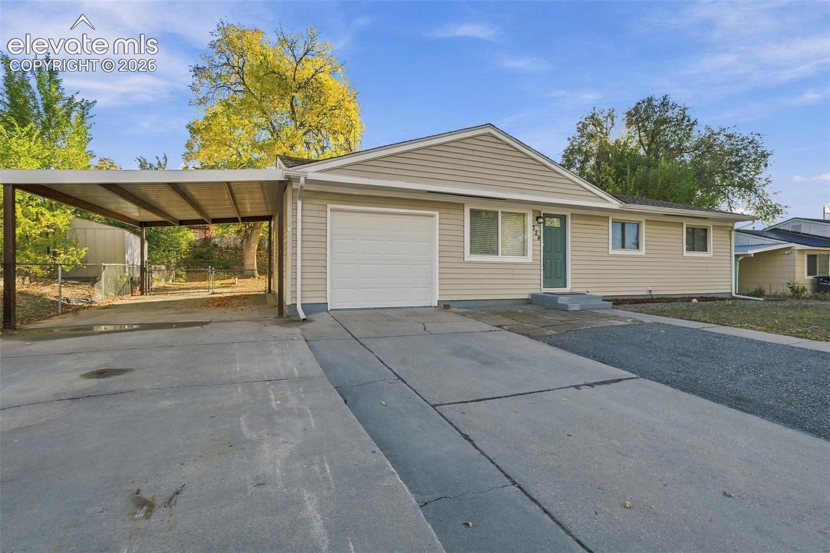 Single-story exterior featuring light-toned horizontal siding, a covered carport, an attached garage, and a paved concrete driveway
