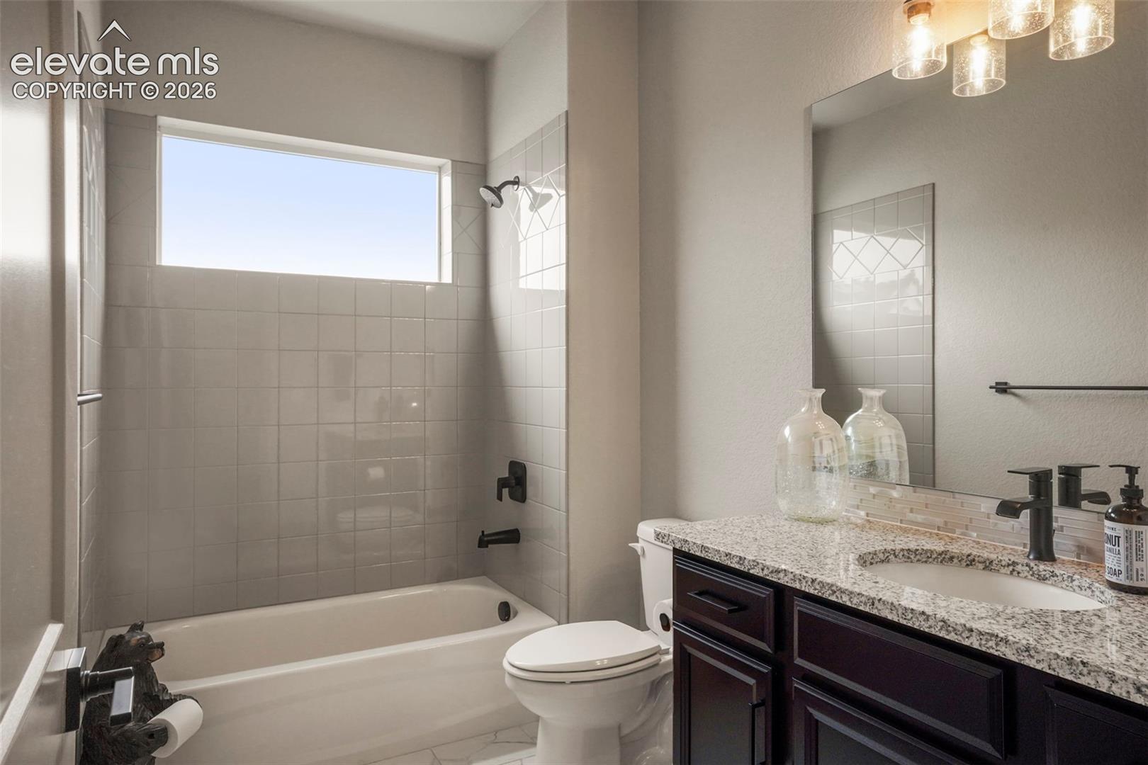 Bathroom featuring a tub/shower combination with subway tile surround, an elongated window, and matte black fixtures